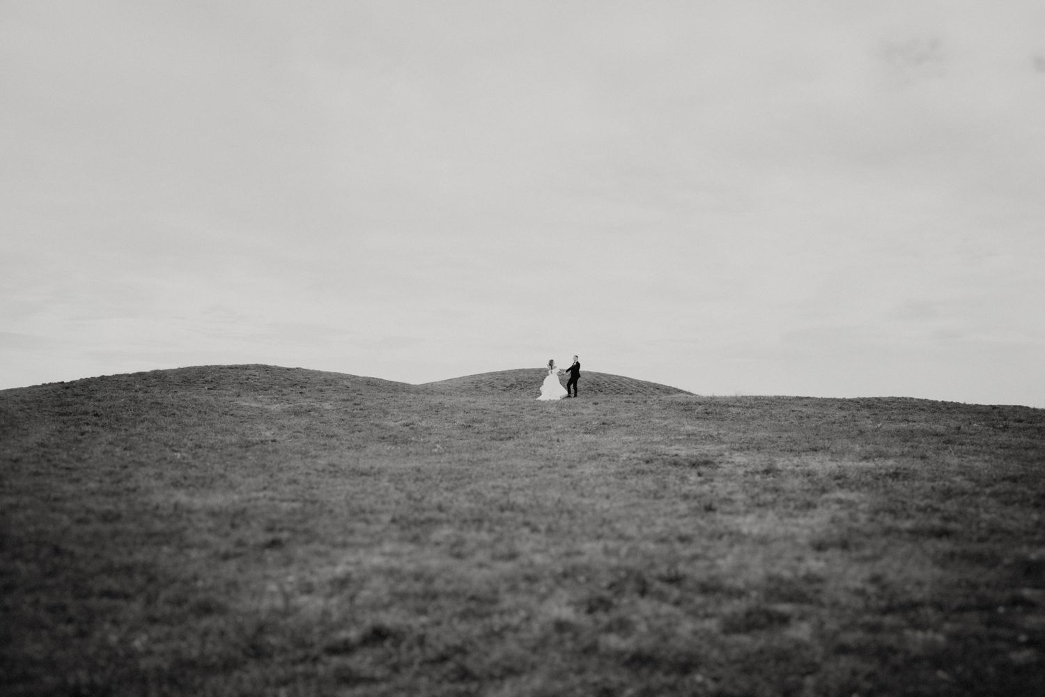 Dramatic black and white landscape photo of rolling hills and distant mountains.