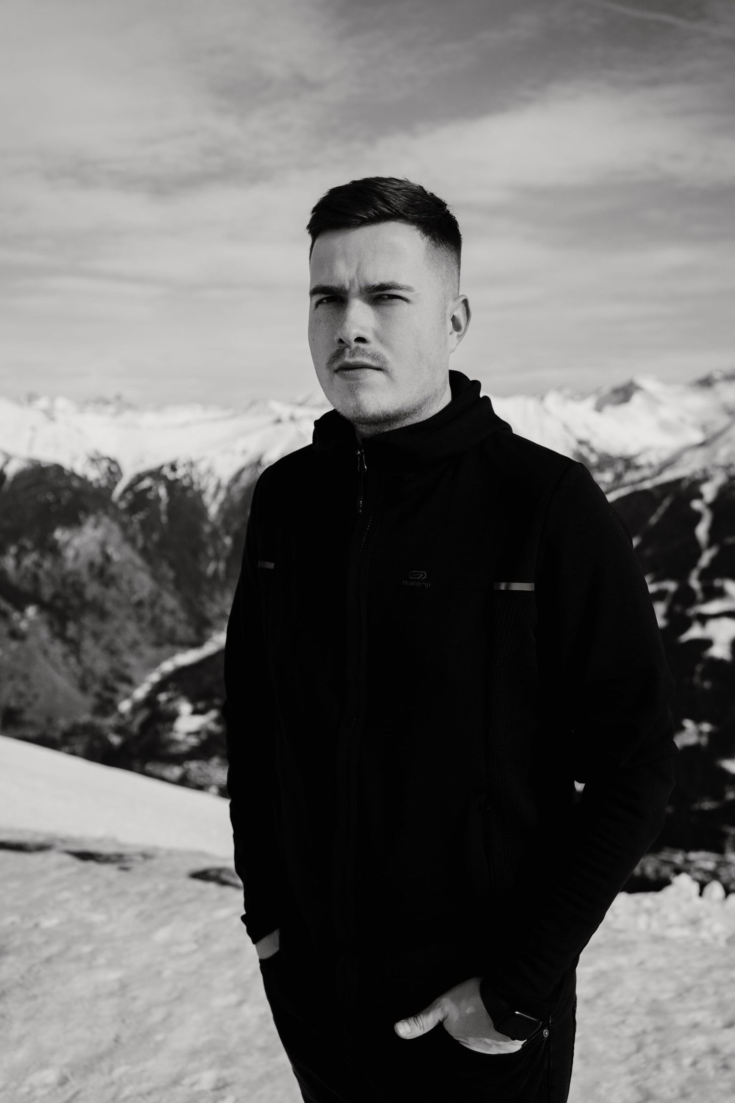 Winter portrait against snowy mountain backdrop with person in black jacket.