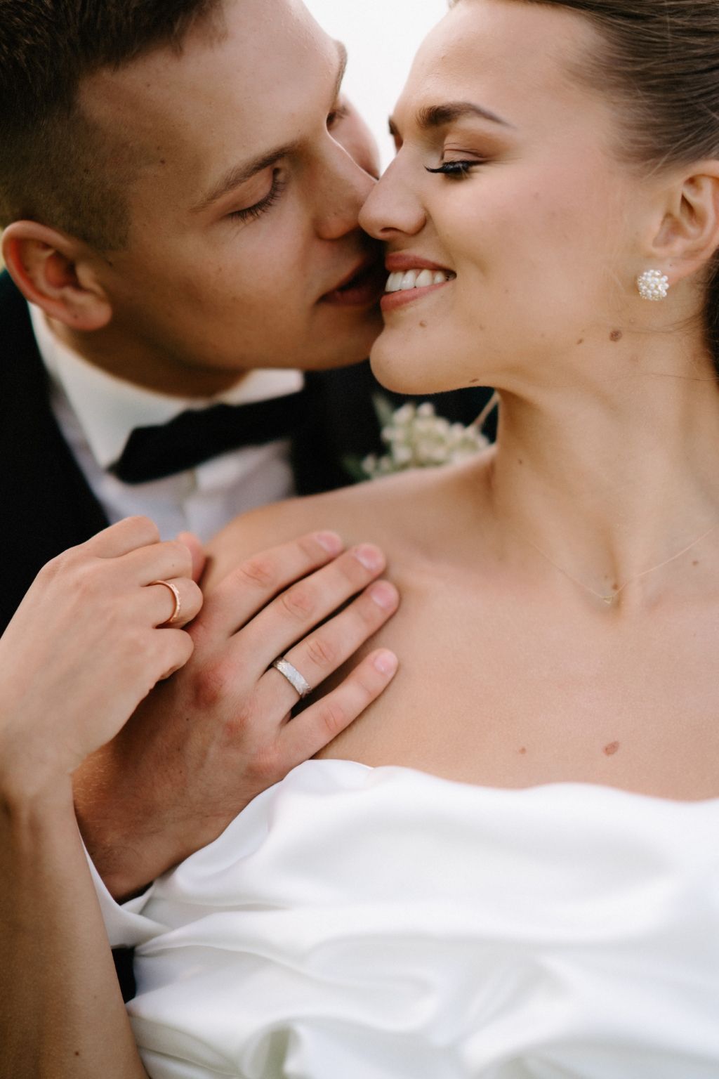 Intimate close-up of a romantic wedding moment showing rings and formal attire.