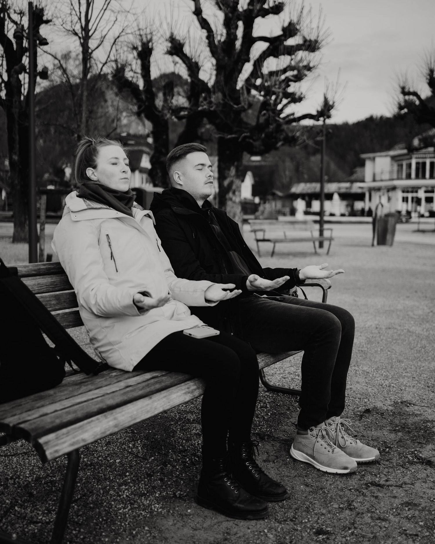 Black and white photo of people relaxing on park benches.