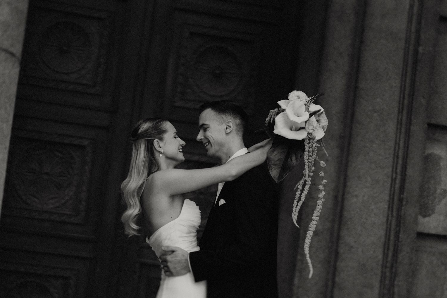 A romantic black and white dance pose in front of an ornate doorway.