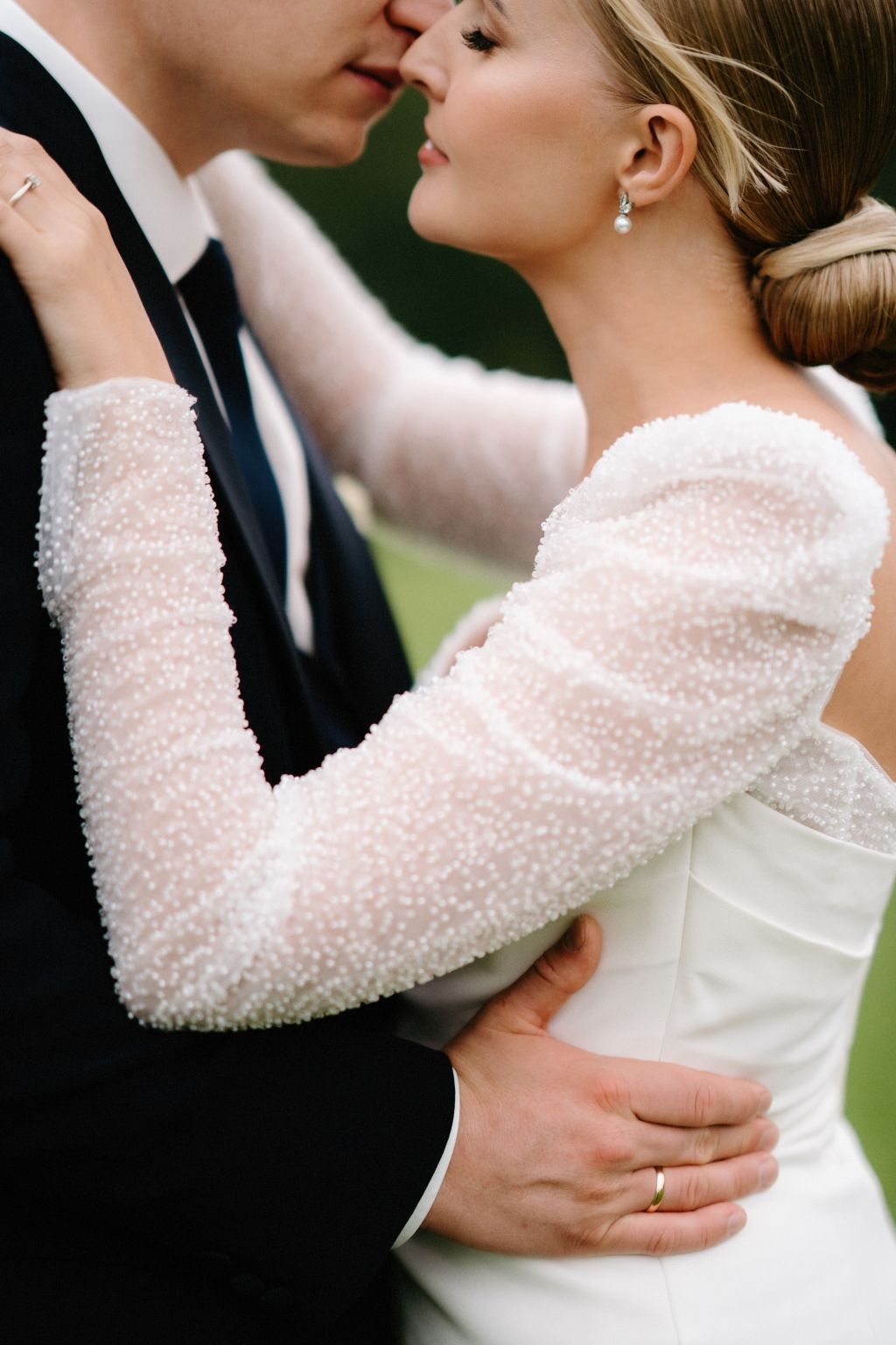 Intimate moment between newlyweds showcasing the bride's textured long-sleeve gown.