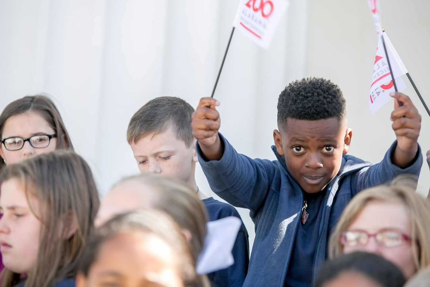 Participants hold up signs during a meeting or gathering while sitting in an audience.