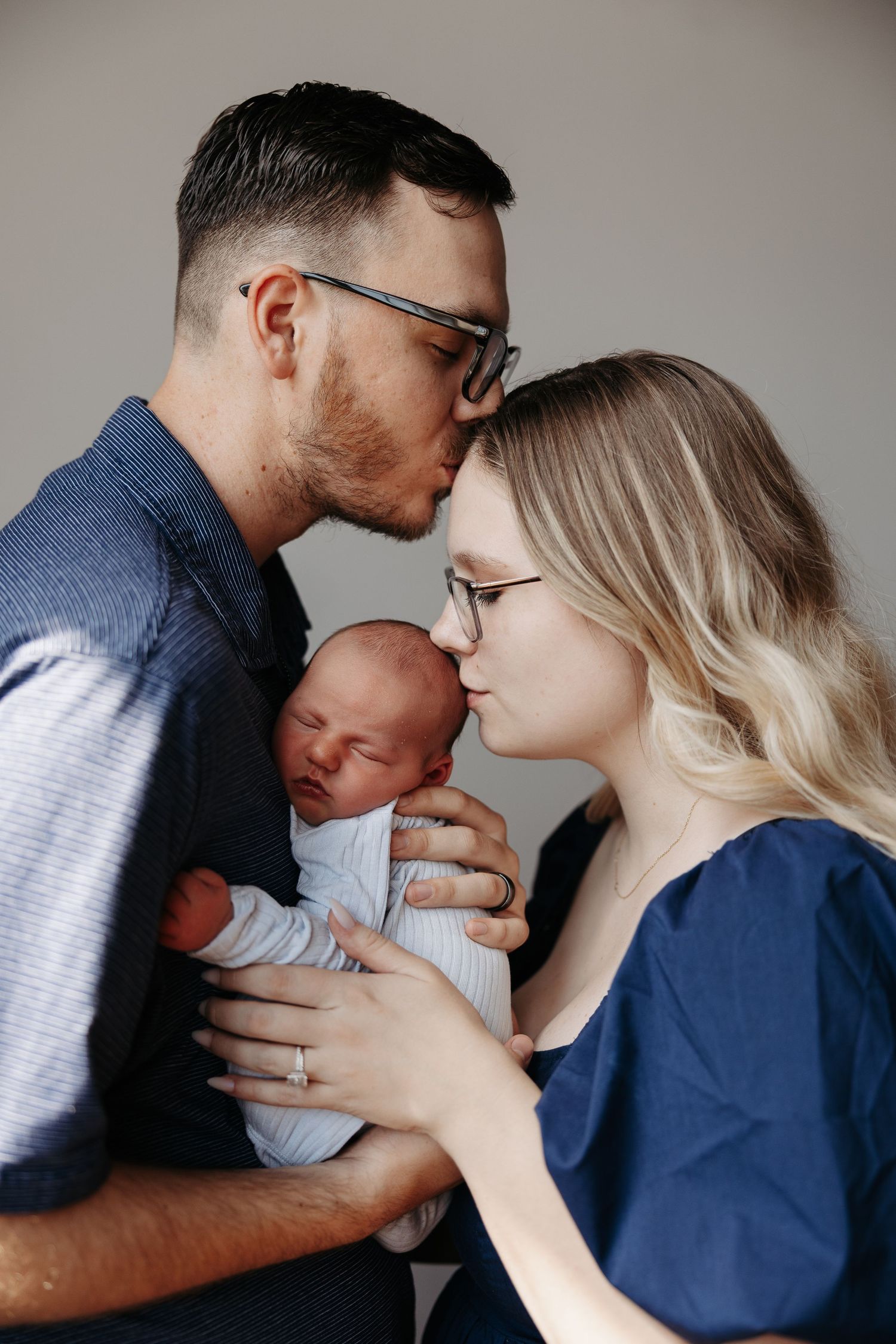 A tender family moment captured in a series of five intimate photos showing parents with their baby against a neutral background.