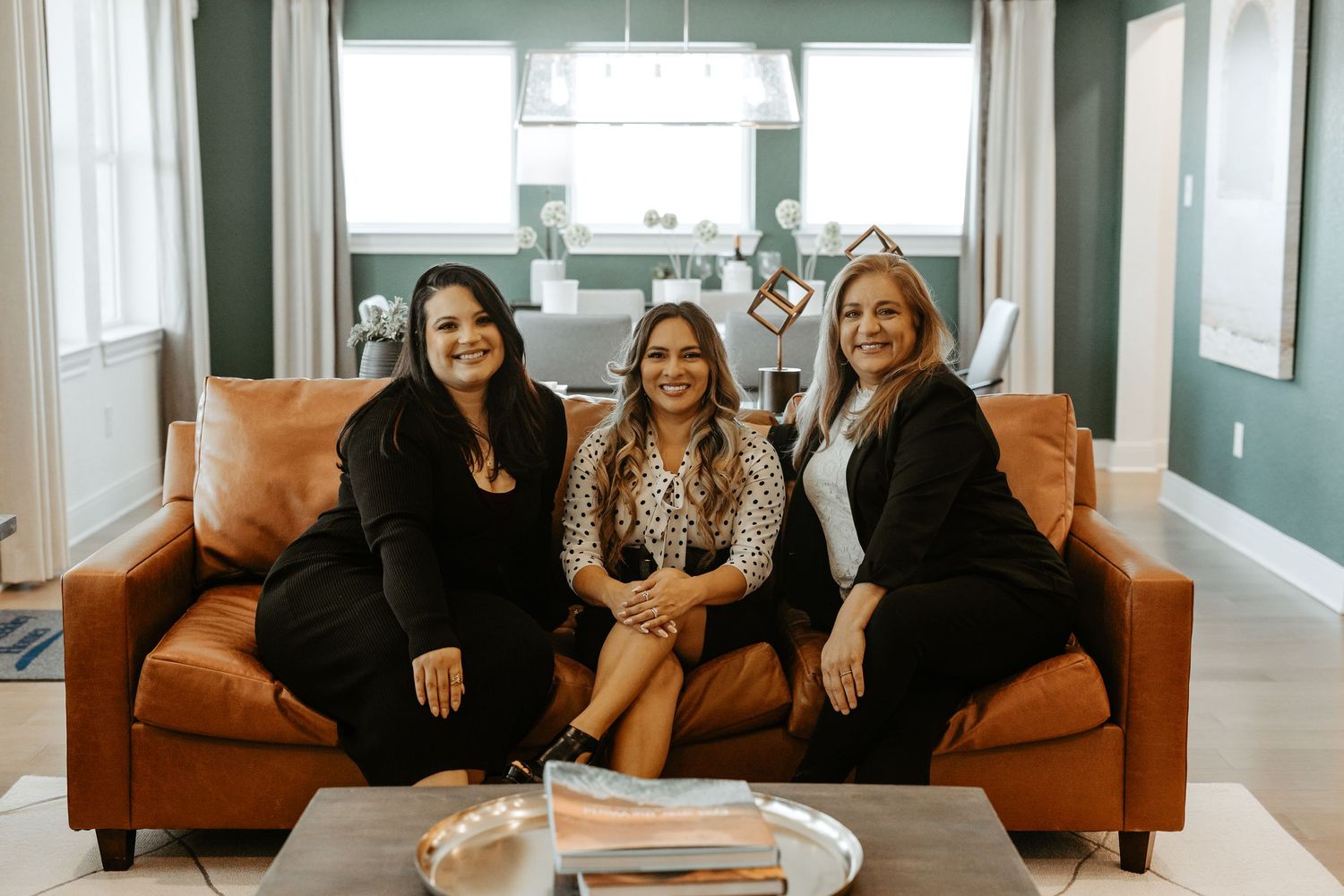 Group sitting on brown leather couches in a bright modern living room.