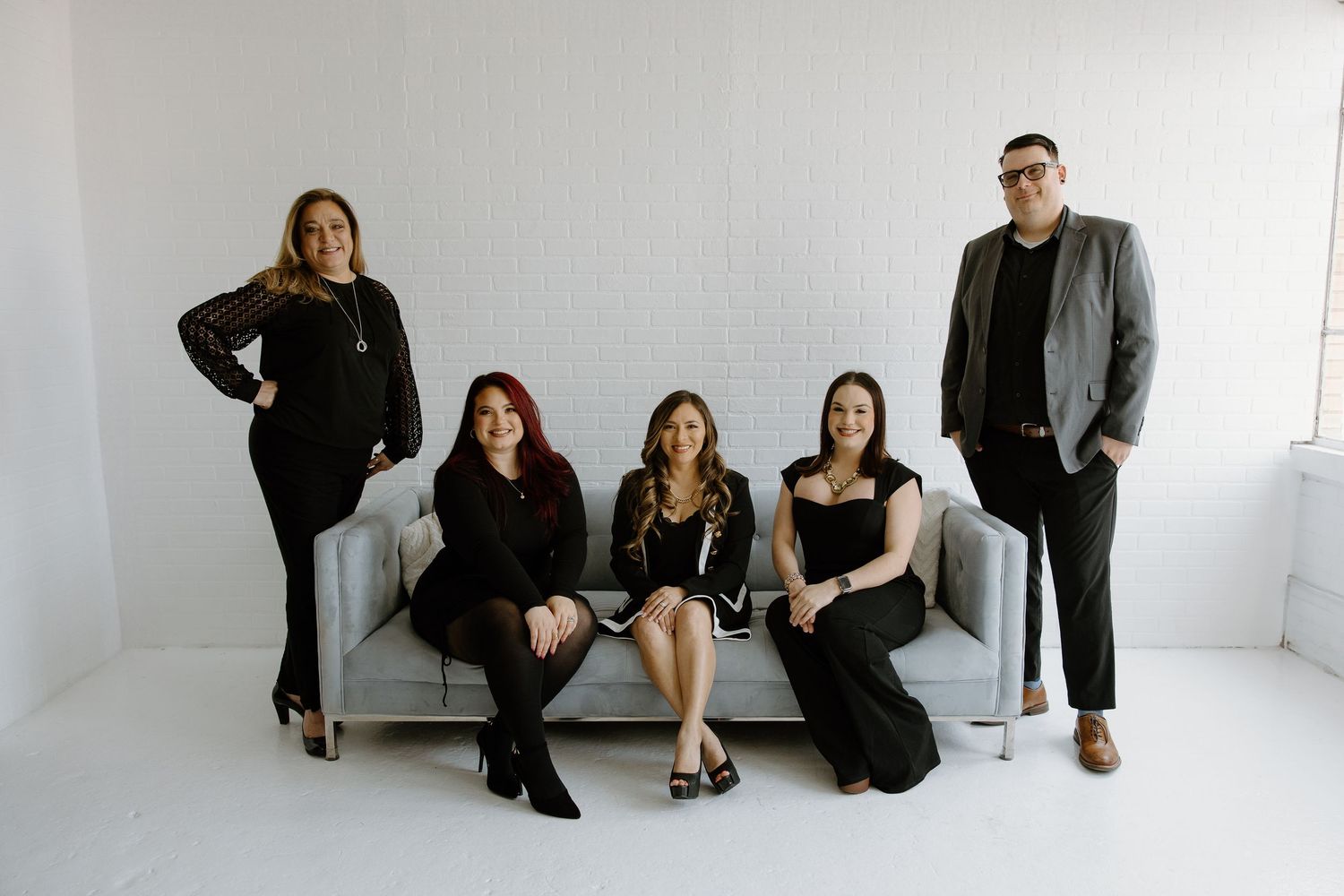 Professional group sits and stands in stylish business attire against a minimalist white backdrop.
