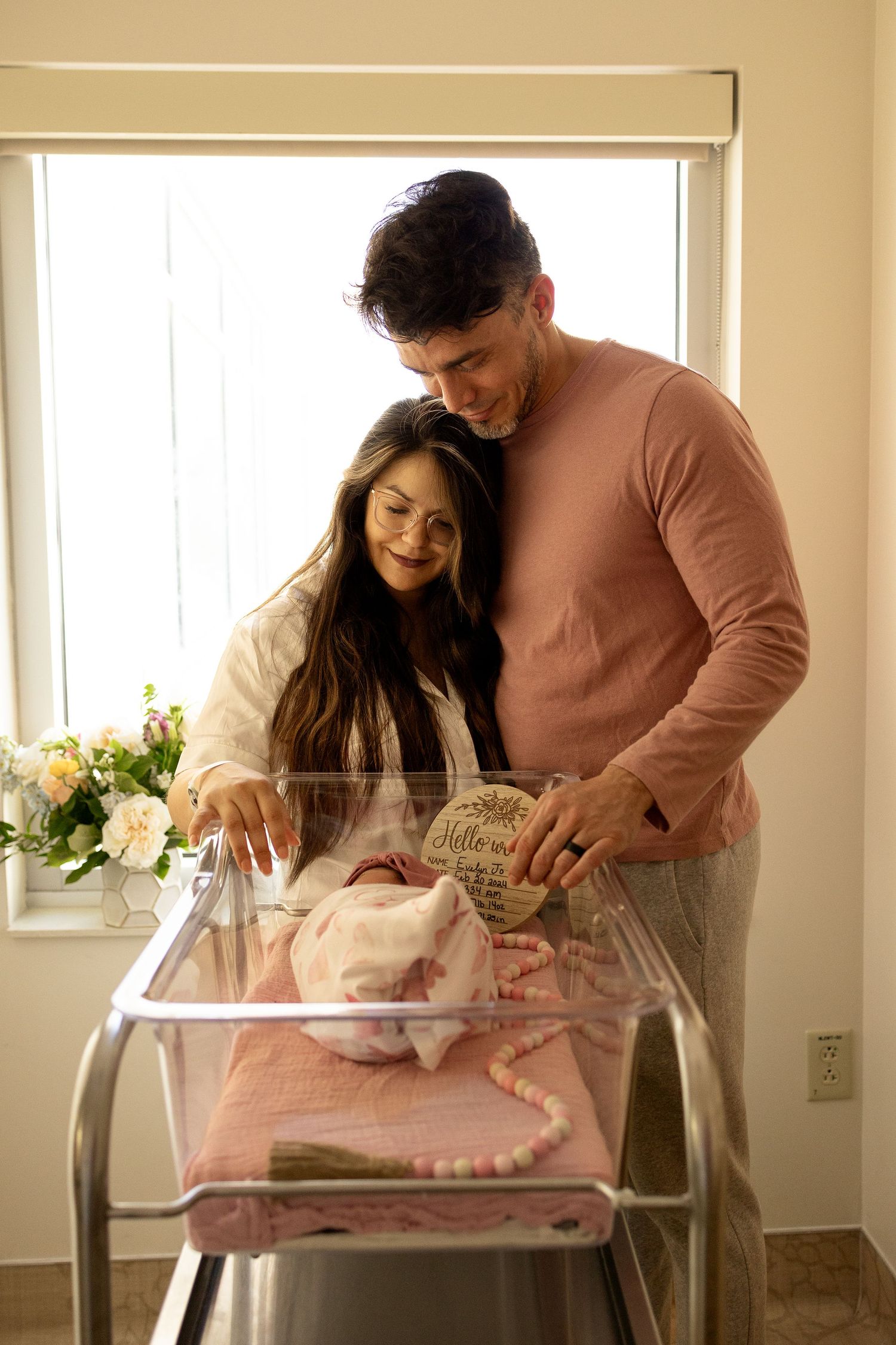Couple looking at baby items in a hospital bassinet.