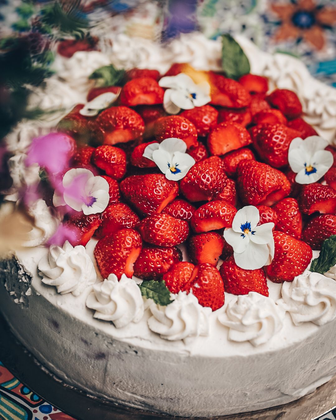 A beautifully decorated white cake topped with fresh strawberries and delicate white flowers.