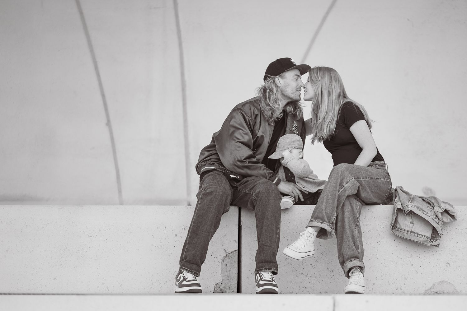 A couple in casual clothing sitting close together share an intimate moment in black and white photography.