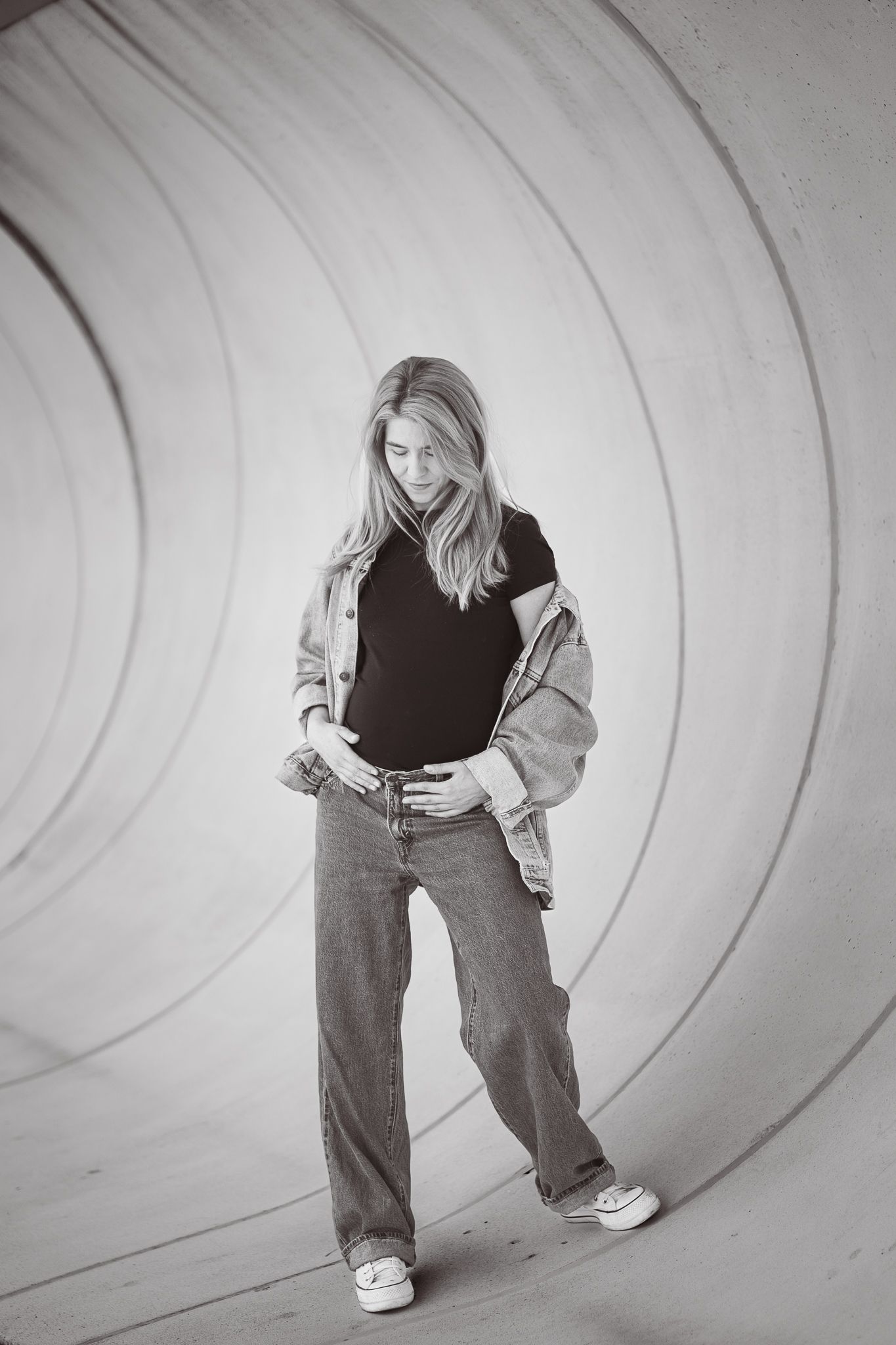 Black and white fashion portrait of a casual outfit with denim jeans, jacket and t-shirt against a curved background.