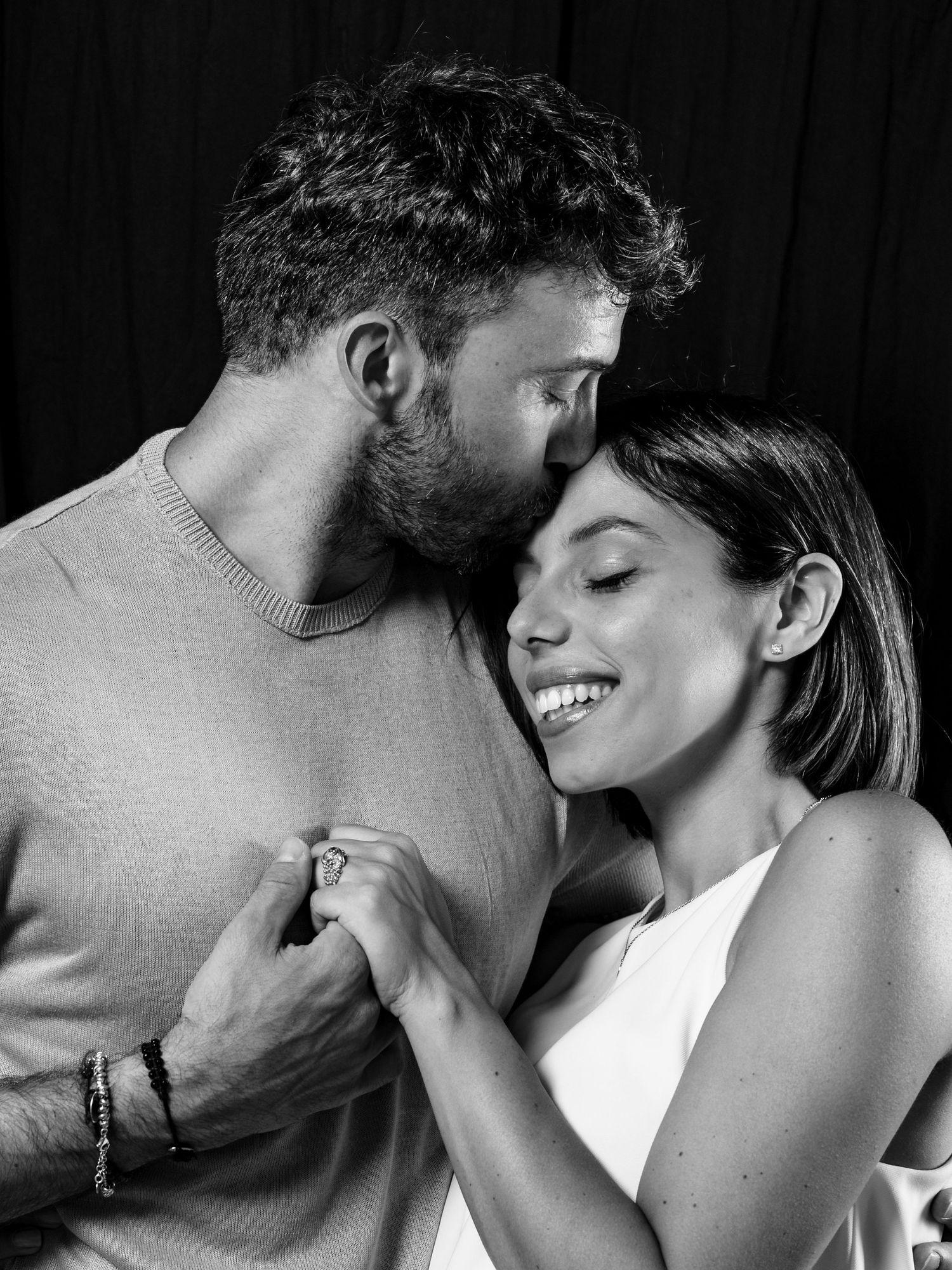 Black and white romantic portrait of a couple sharing an intimate moment while holding hands and smiling.