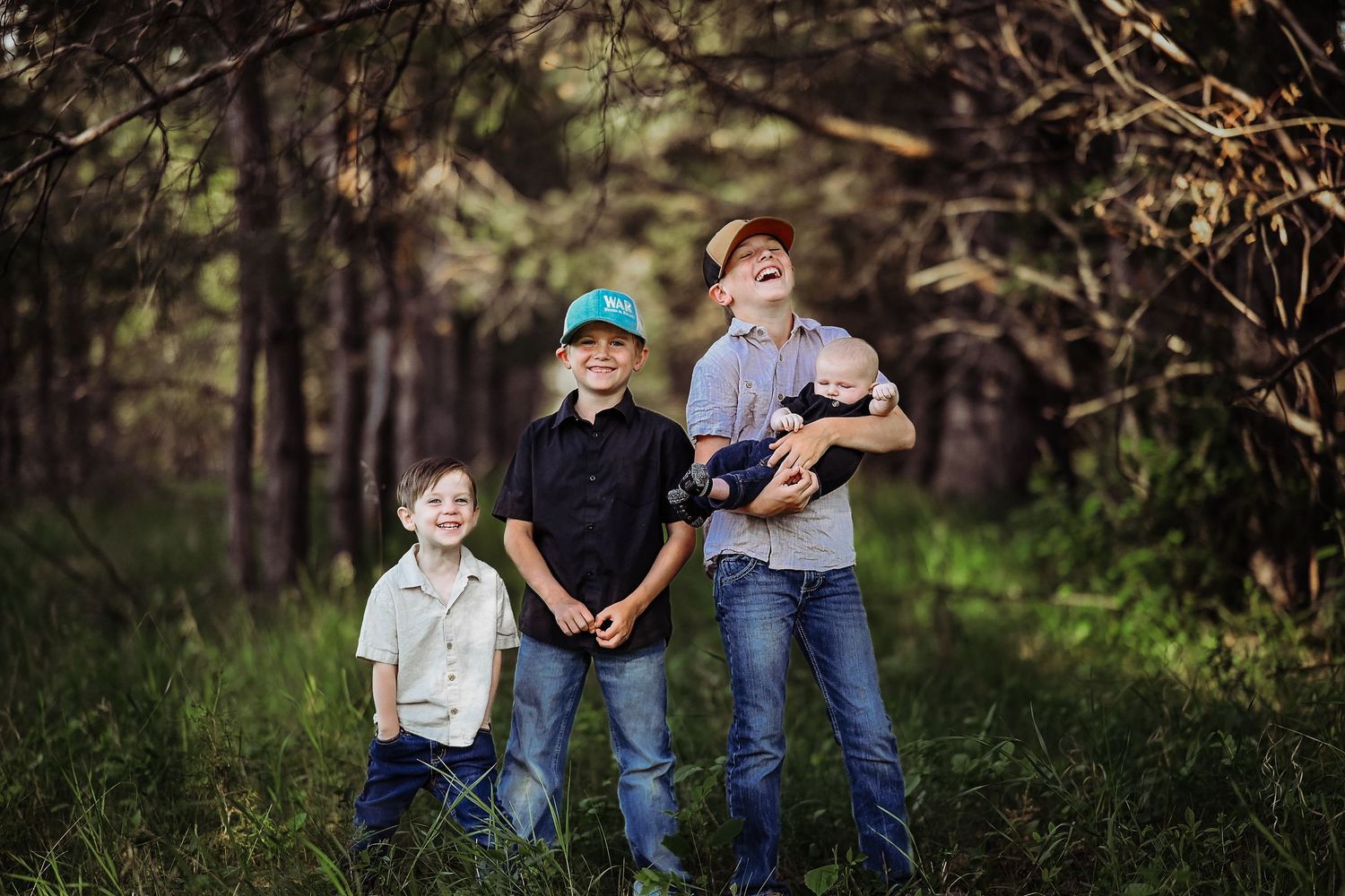 Three young people in casual clothing standing together in a wooded forest setting during daytime.