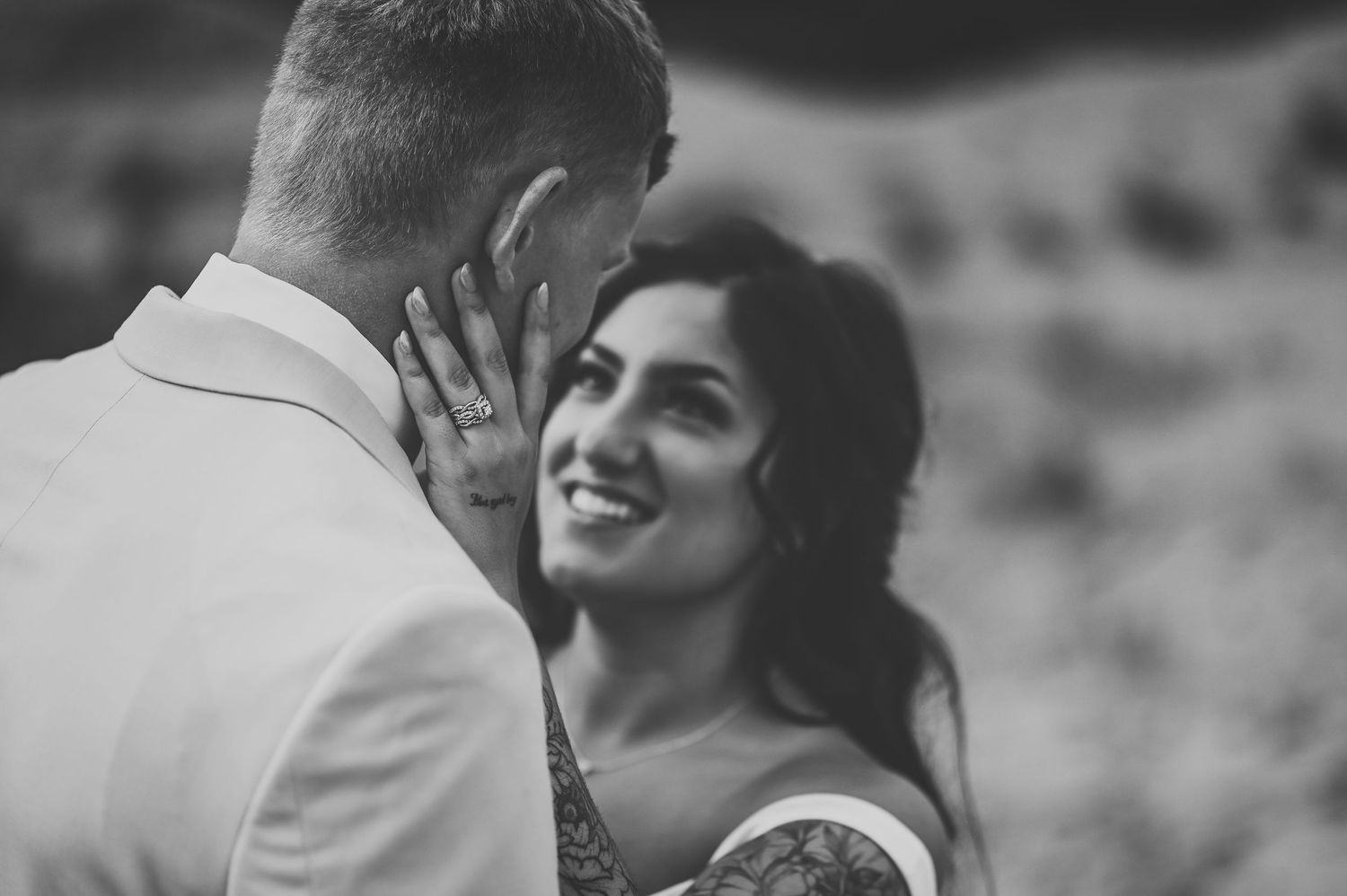 Black and white romantic portrait of a wedding couple embracing and sharing an intimate moment outdoors.
