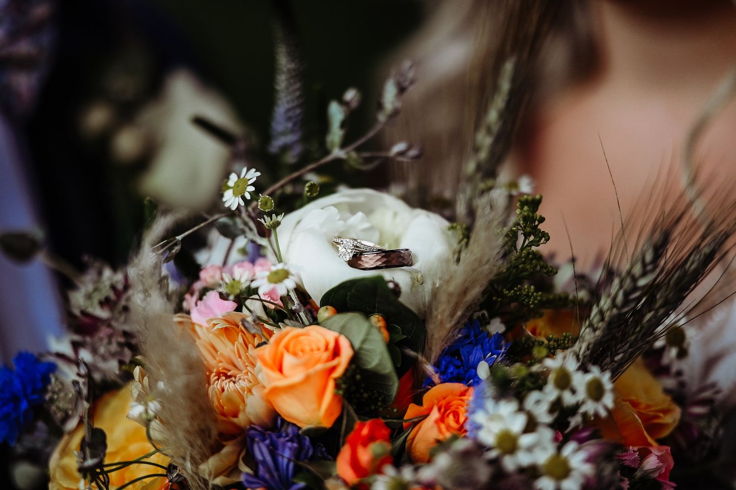 Vibrant floral arrangements featuring roses, lilies, and wildflowers in peach and orange tones create a romantic display.