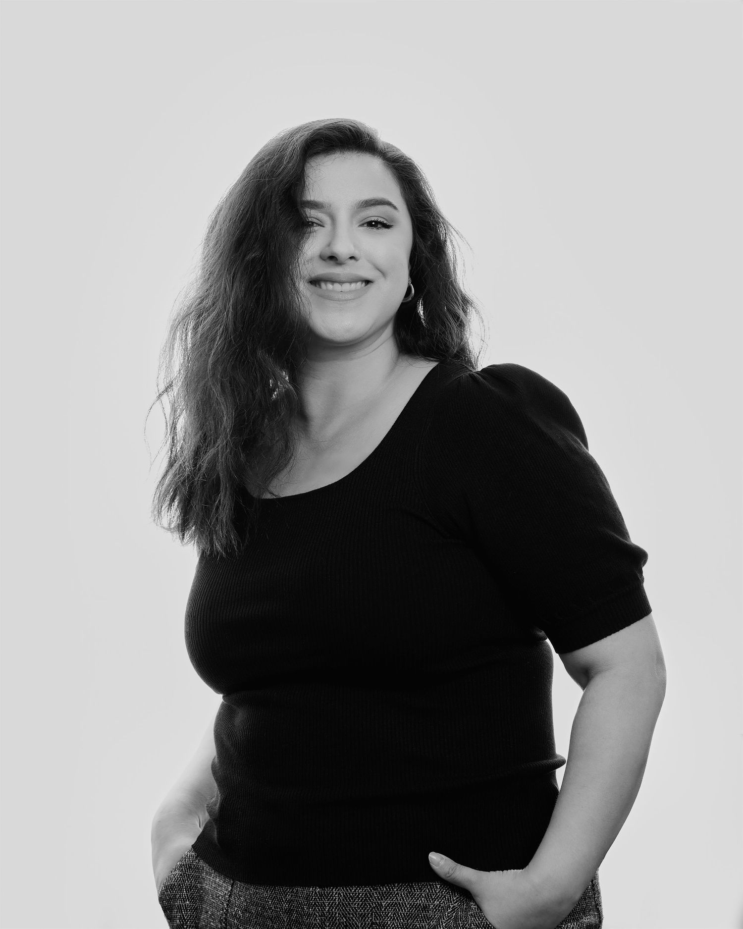 Joyful studio portrait in black and white featuring woman in dark top.