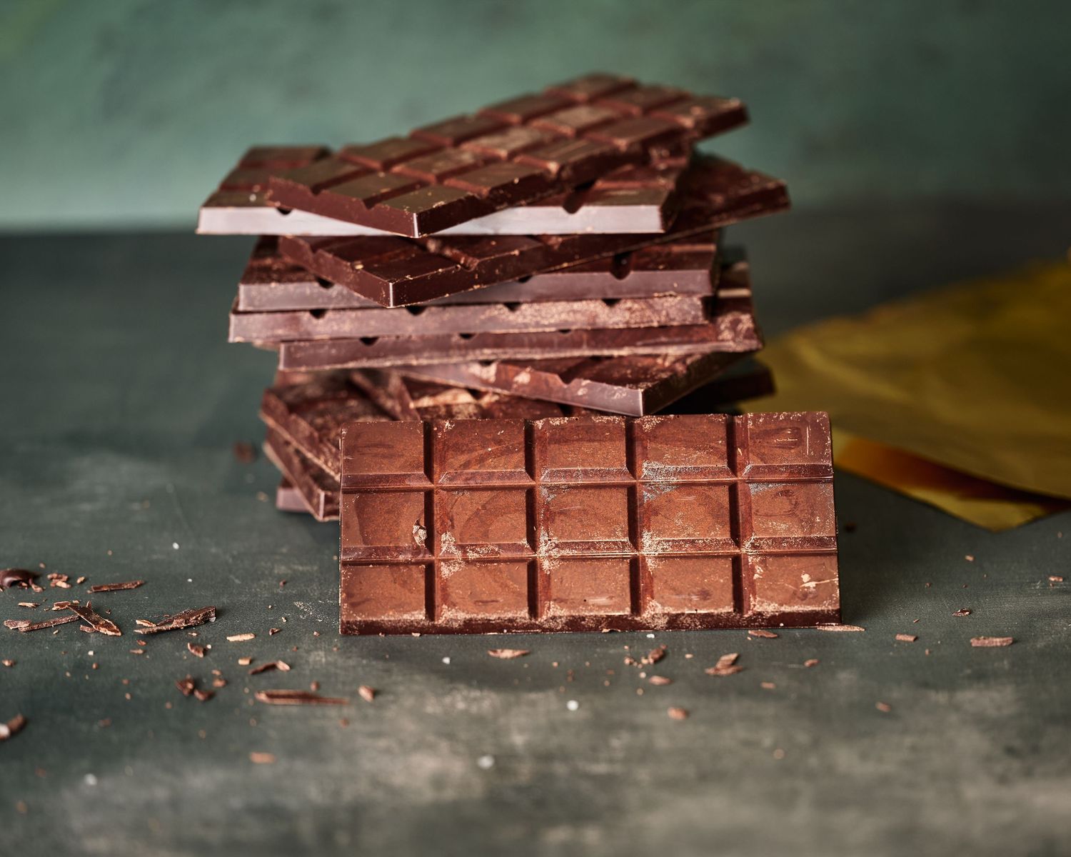 Stacked chocolate bars with textured squares photographed on a dark surface.