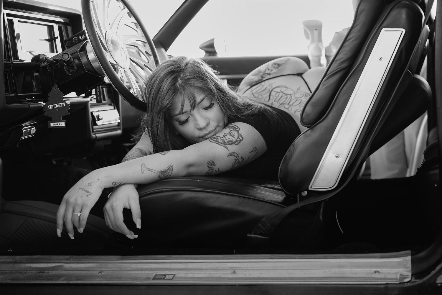 A black and white photo compilation shows someone sleeping in different positions inside a car with visible tattoos.