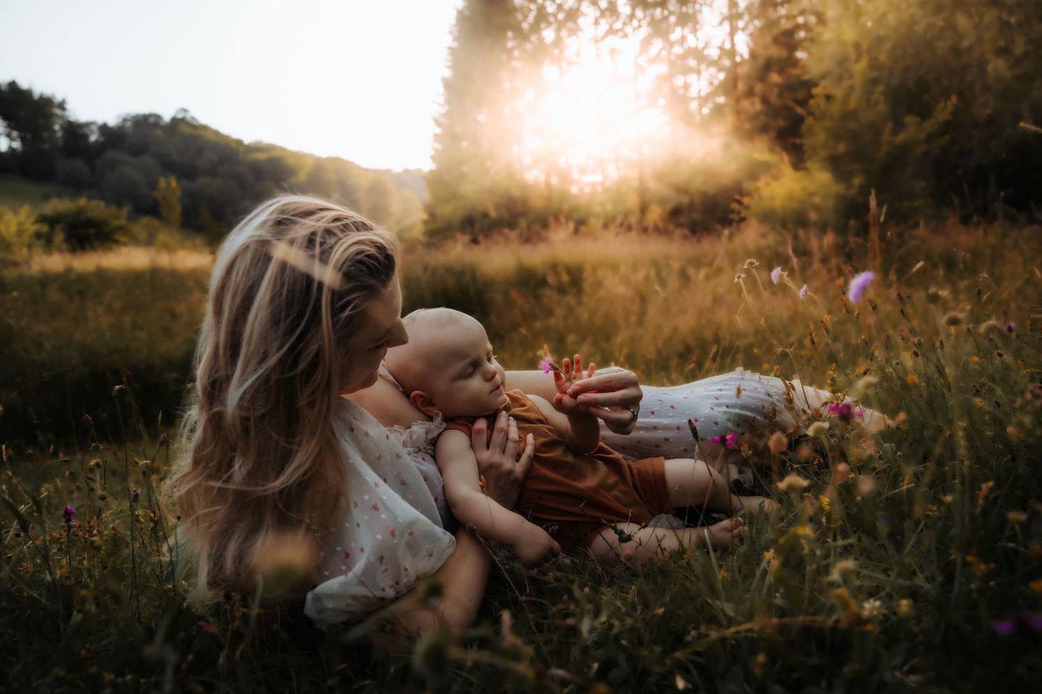A peaceful golden hour moment in a wildflower meadow with a picnic blanket and loved ones enjoying nature at sunset.