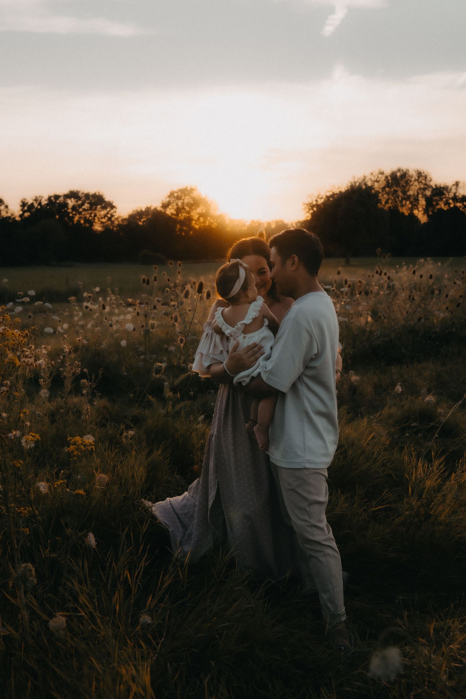 A loving family portrait silhouetted against a golden sunset in a meadow.