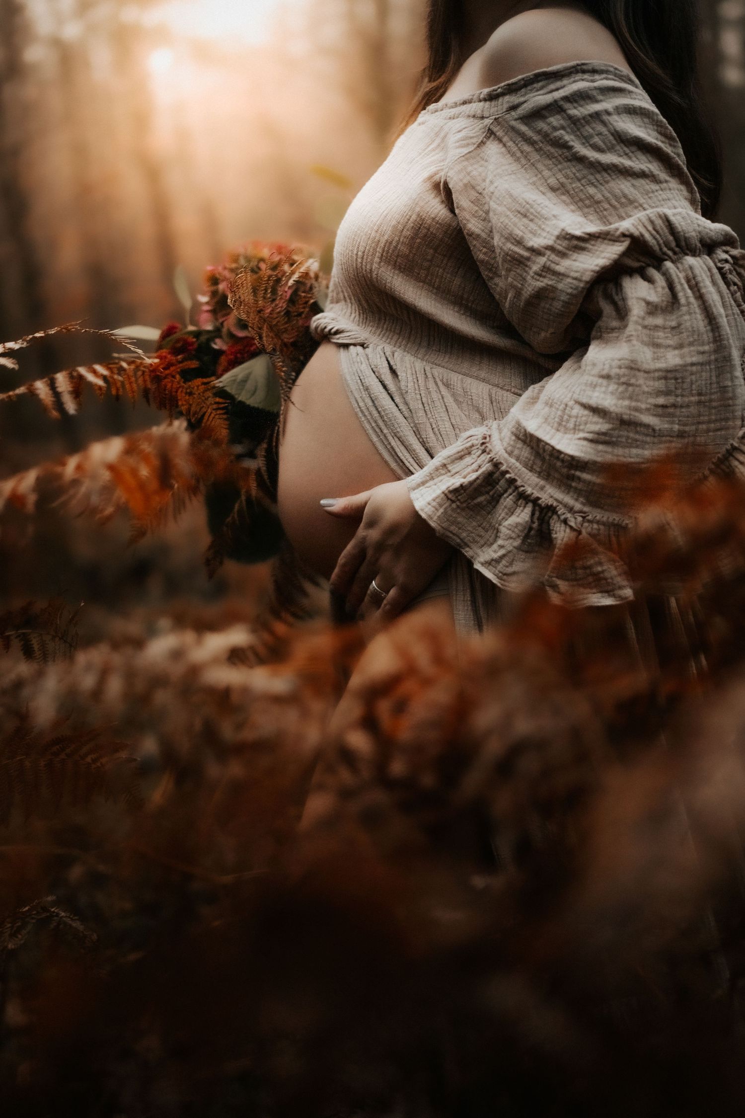 A person in casual clothing lies on autumn leaves creating a dreamy, artistic outdoor portrait in warm tones.