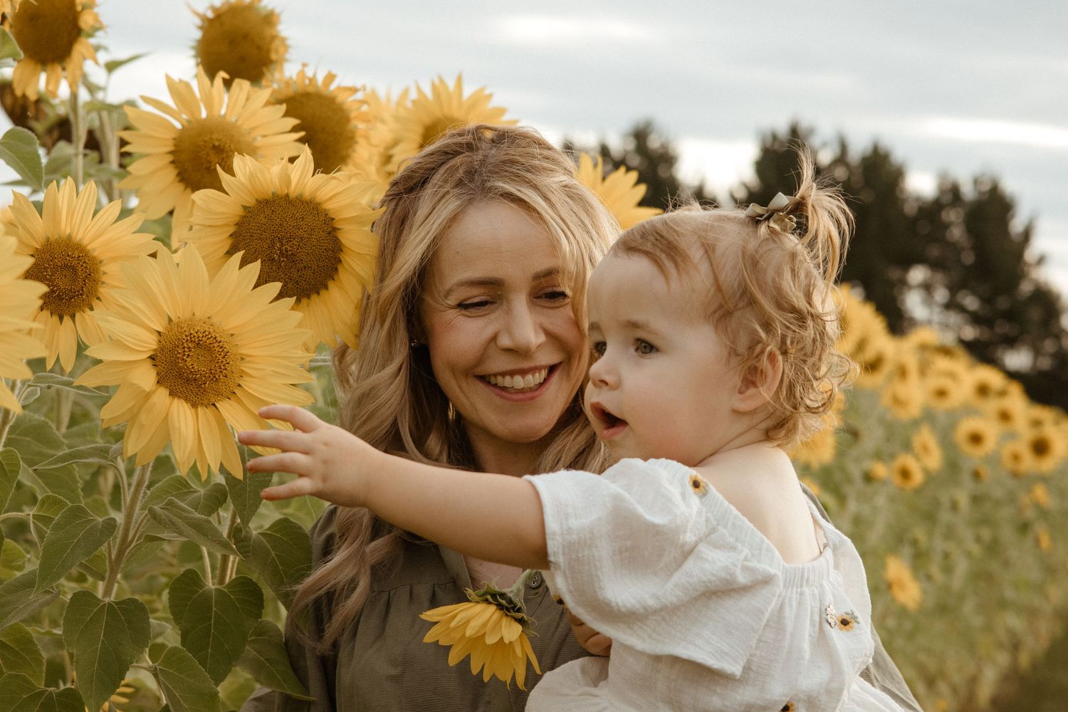 Joyful moment in a sunflower field with bright yellow blooms against an overcast sky.