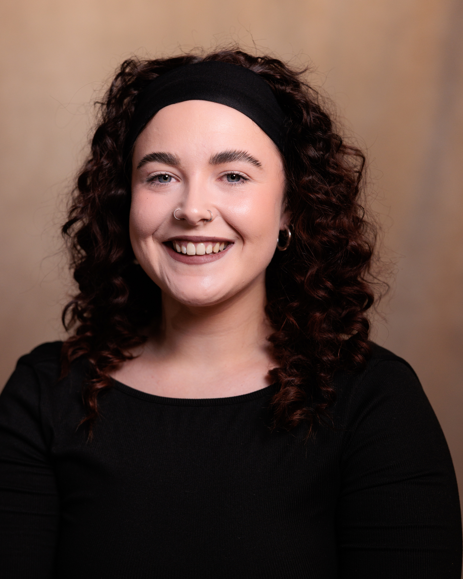 Portrait series showing person with curly dark hair and black top against neutral background expressing different emotions.