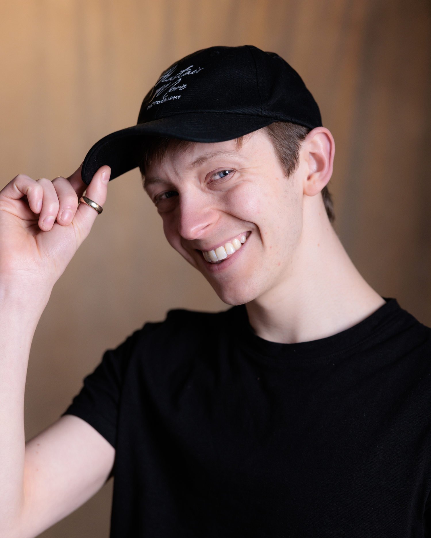 A series of five profile shots showing someone in a black shirt and cap adjusting their hat while smiling.