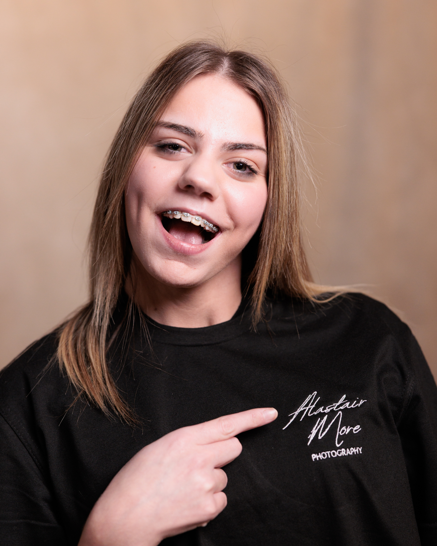 A series of playful expressions showing joy and laughter while wearing a black top against a neutral background.