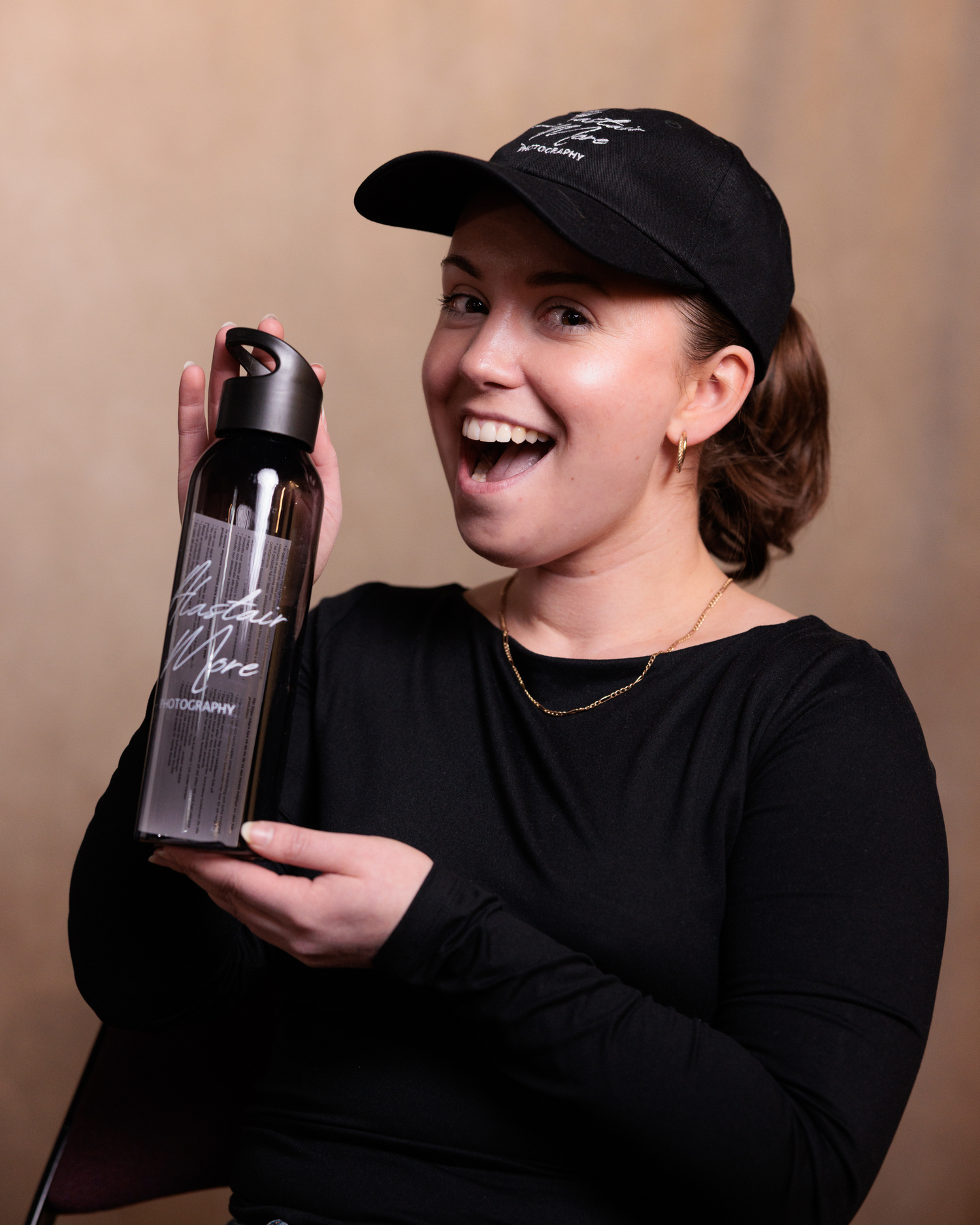 A person wearing a black sweater and baseball cap poses with a metallic drink container in a series of playful shots.