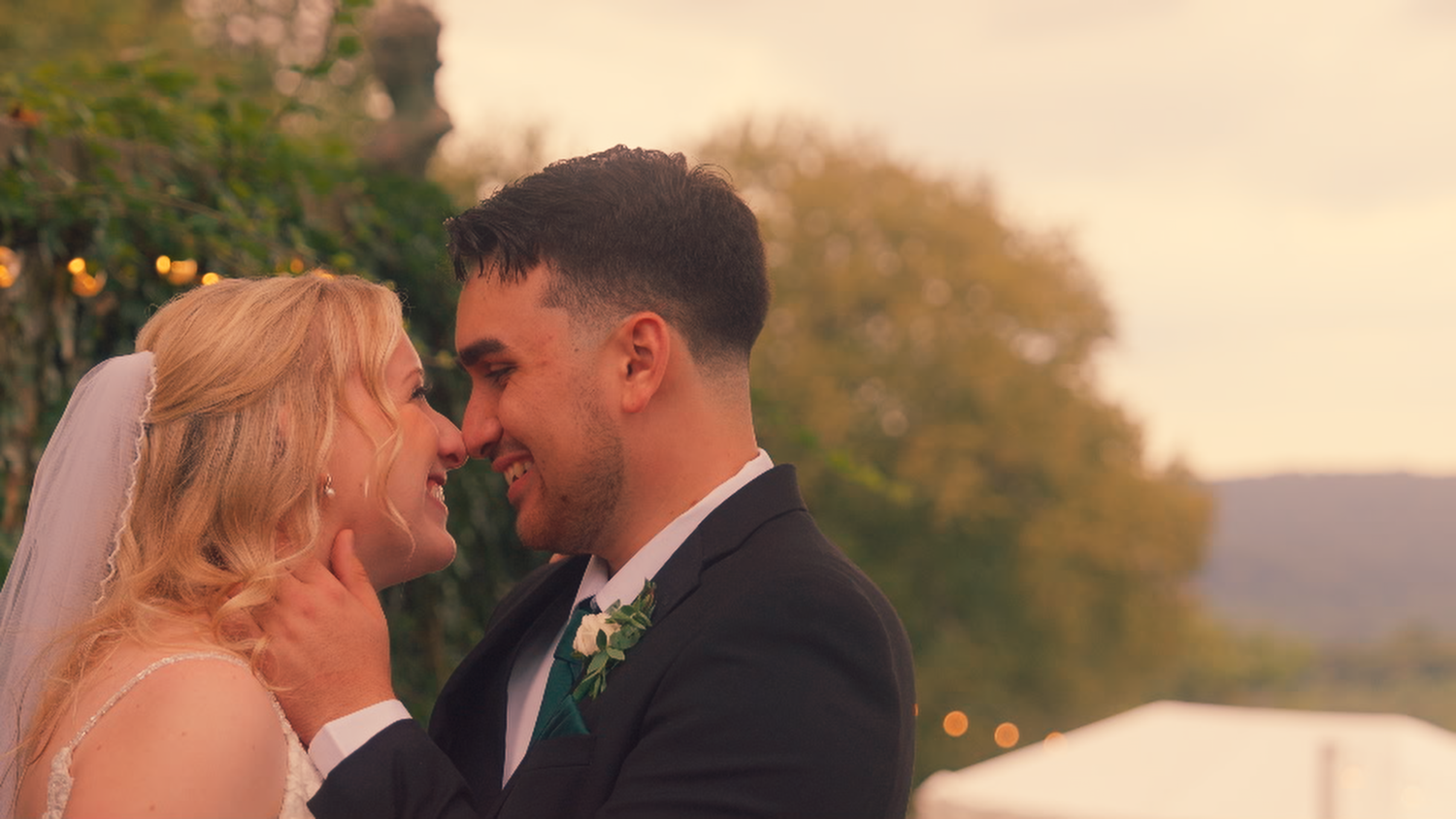 Intimate close-up of bride and groom touching foreheads in a candid outdoor moment.