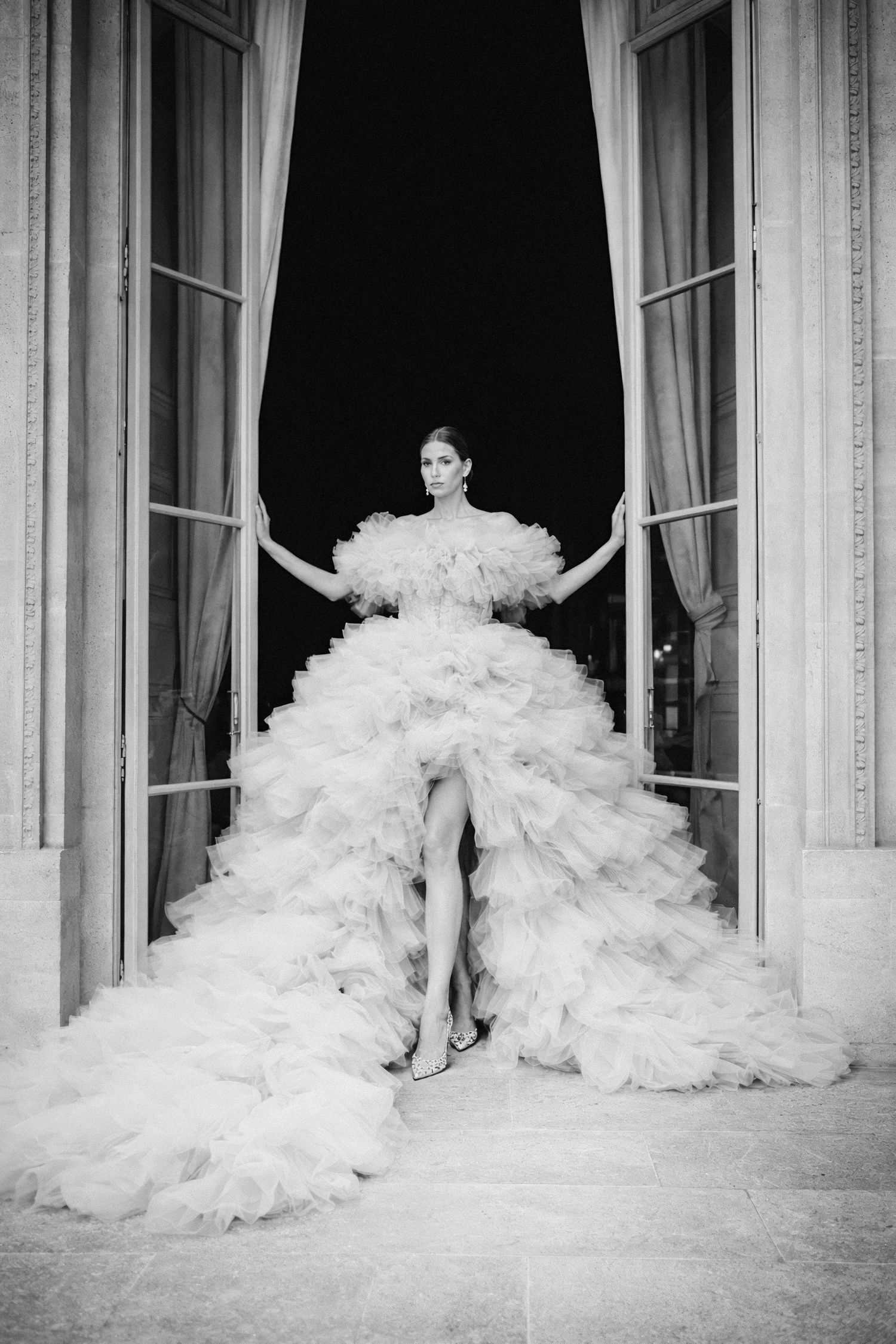 A black and white photo series showing the dramatic movement of a flowing white ballgown against elegant curtained windows.