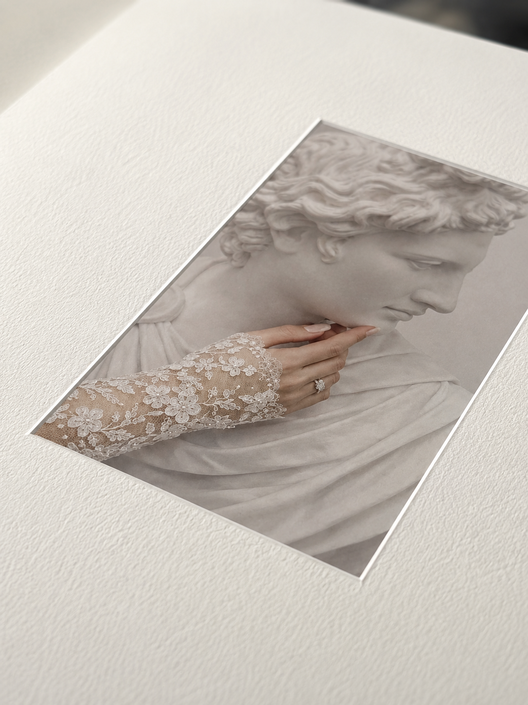 A bride's lace-gloved hand adorned with a diamond ring rests against a classical marble sculpture.
