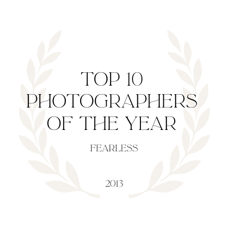 A minimalist circular laurel wreath logo design featuring 'Top 10 Photographers of the Year - Fearless 2013' text.