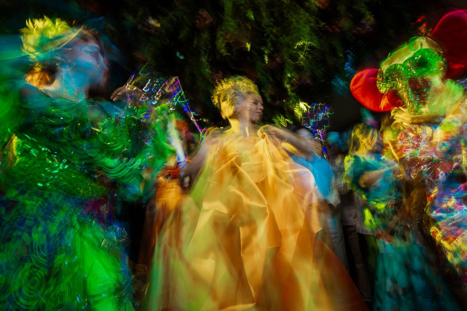 Colorful abstract light painting with swirling streaks of green, blue, yellow and red creating dynamic motion patterns.