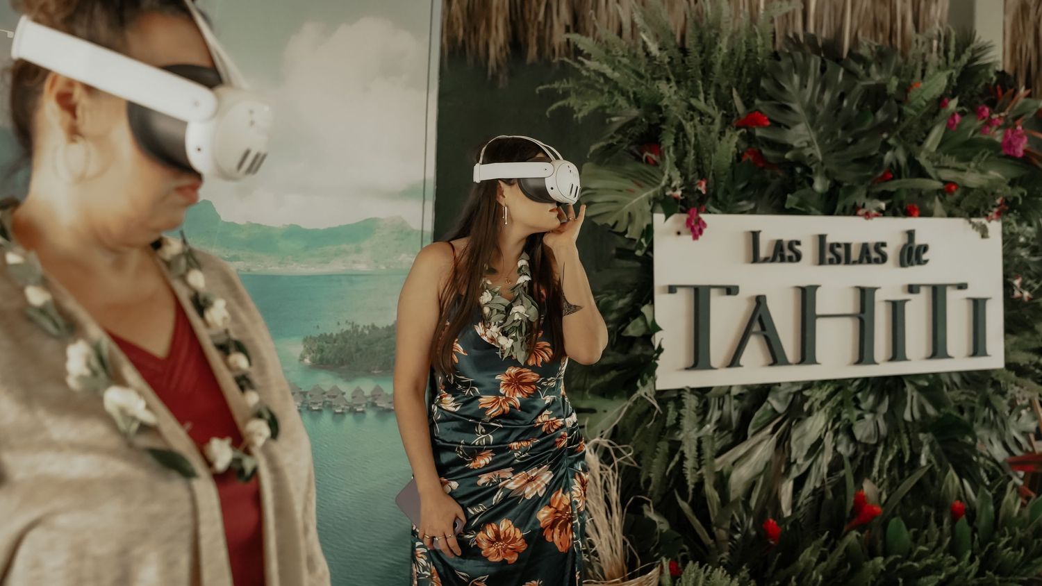 Two women wearing VR headsets at a Las Islas de Tahiti promotional event booth.