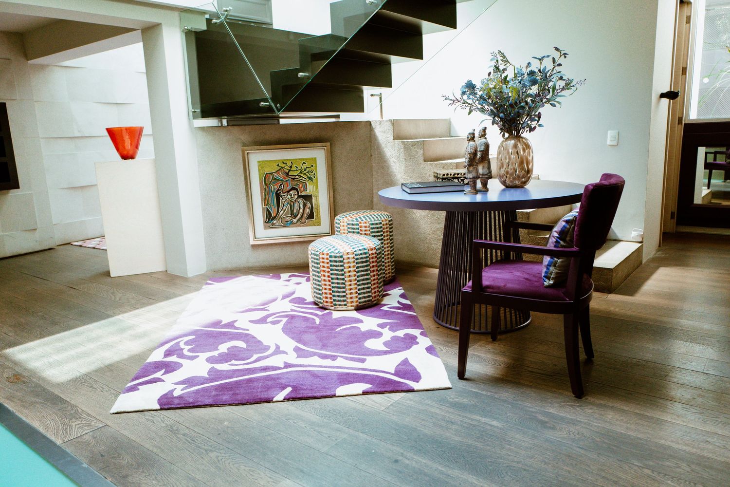 Contemporary split-level living space with purple accent chair, floral rug, and floating staircase.