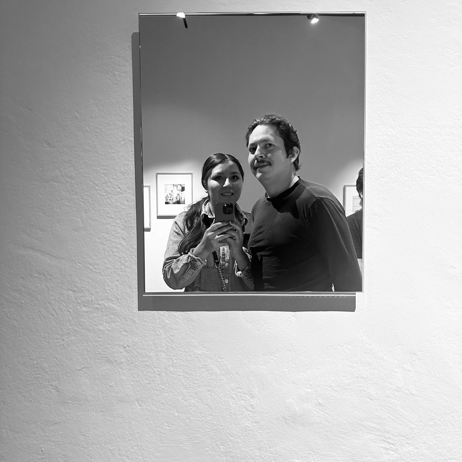 Black and white mirror selfie of couple at photography gallery exhibition opening event.