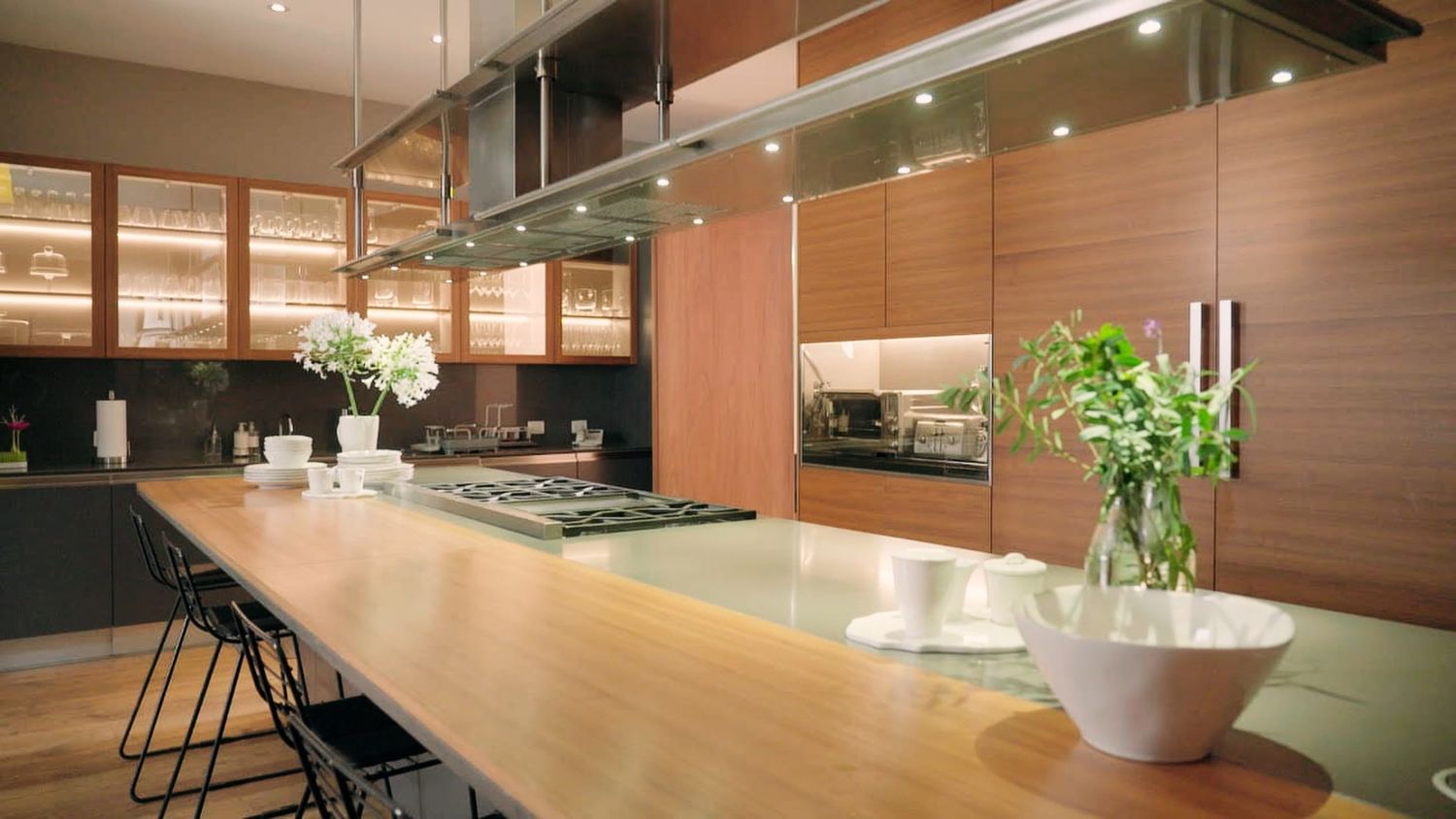 Modern luxury kitchen with wooden cabinetry, long island countertop, pendant lights, and stainless steel appliances.