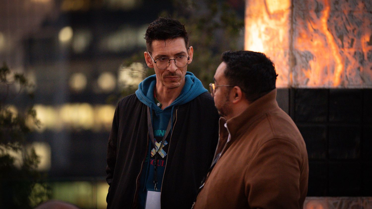 Two men having a conversation at an outdoor evening corporate networking event.