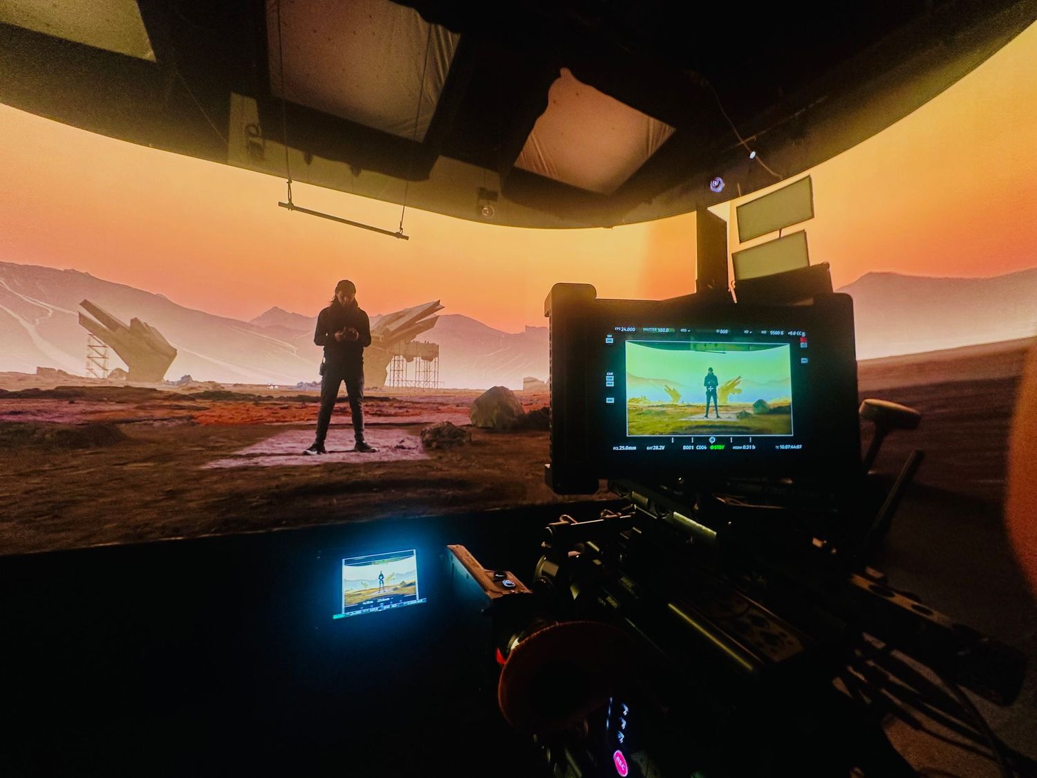 Camera monitor displays actor on Mars-like LED volume stage set during sci-fi film production.