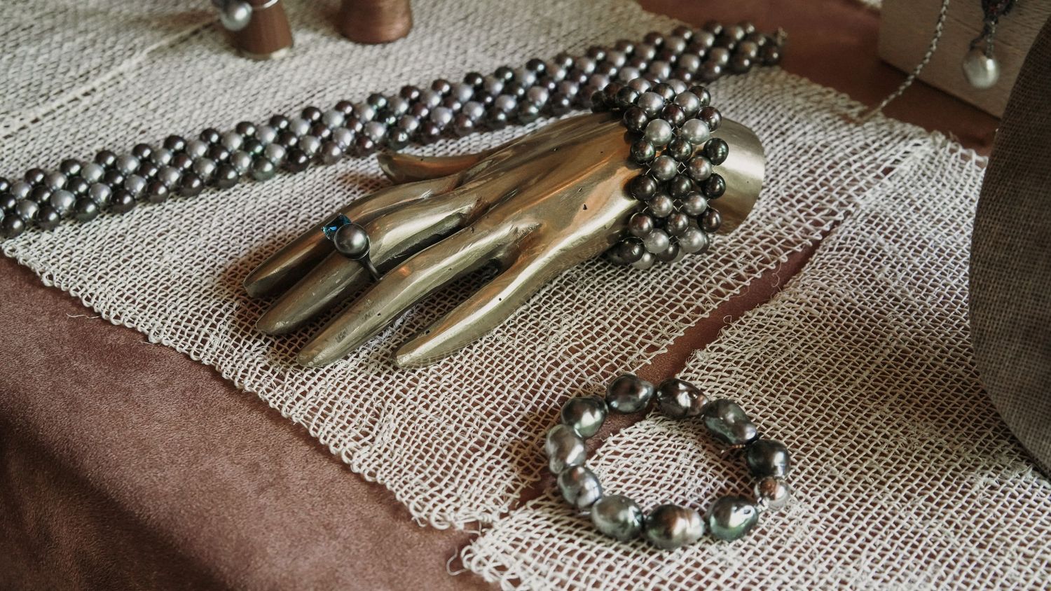 Vintage silver jewelry collection including rings, bracelet and hand-shaped ornament displayed on burlap fabric.