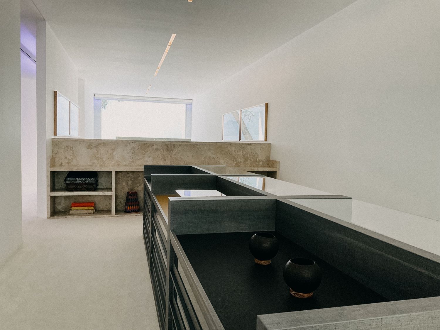 Modern minimalist interior with dark countertop island and stone accent wall with built-in shelving.