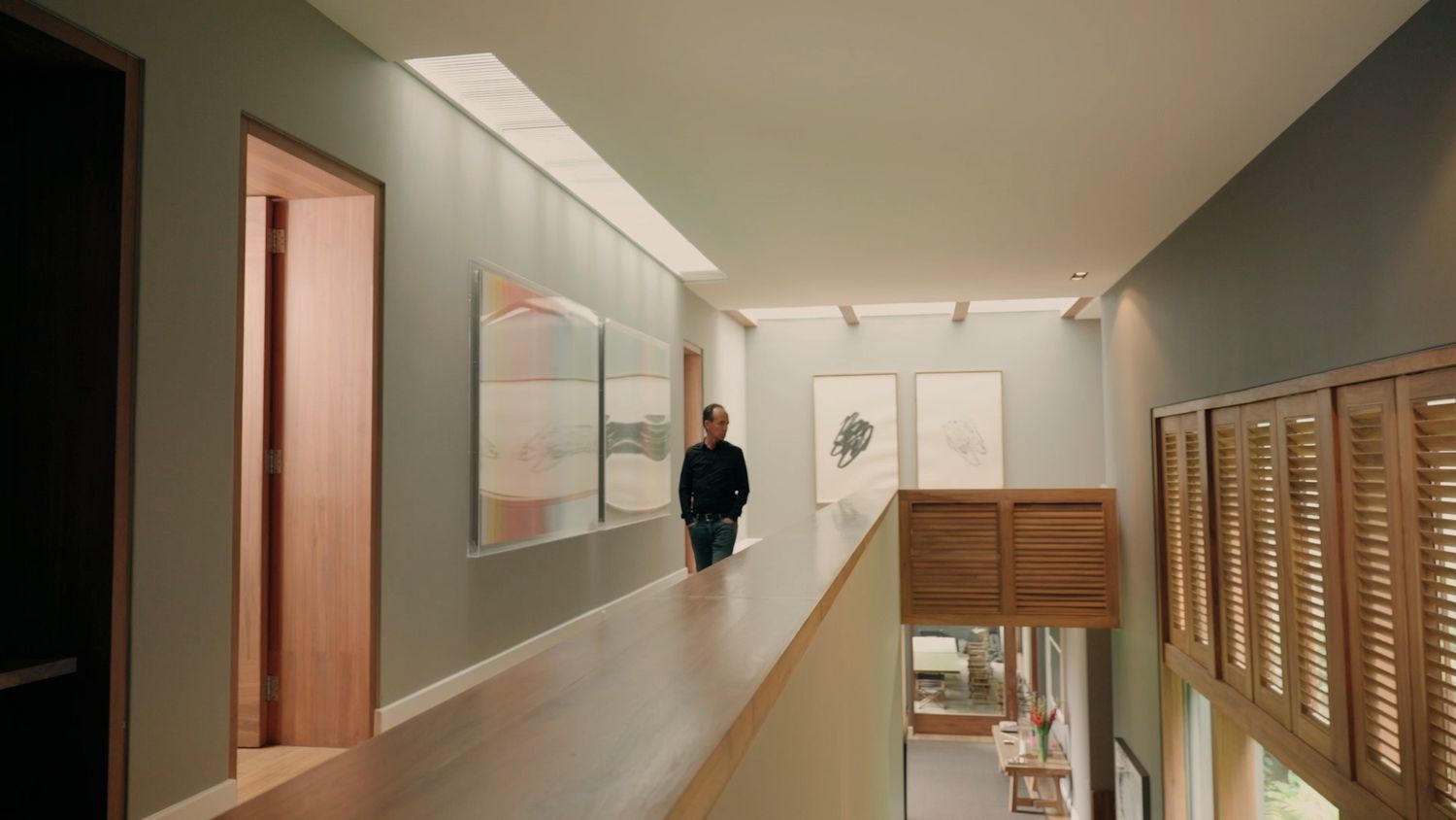 Modern home interior hallway with artwork gallery wall and wooden flooring in neutral tones.