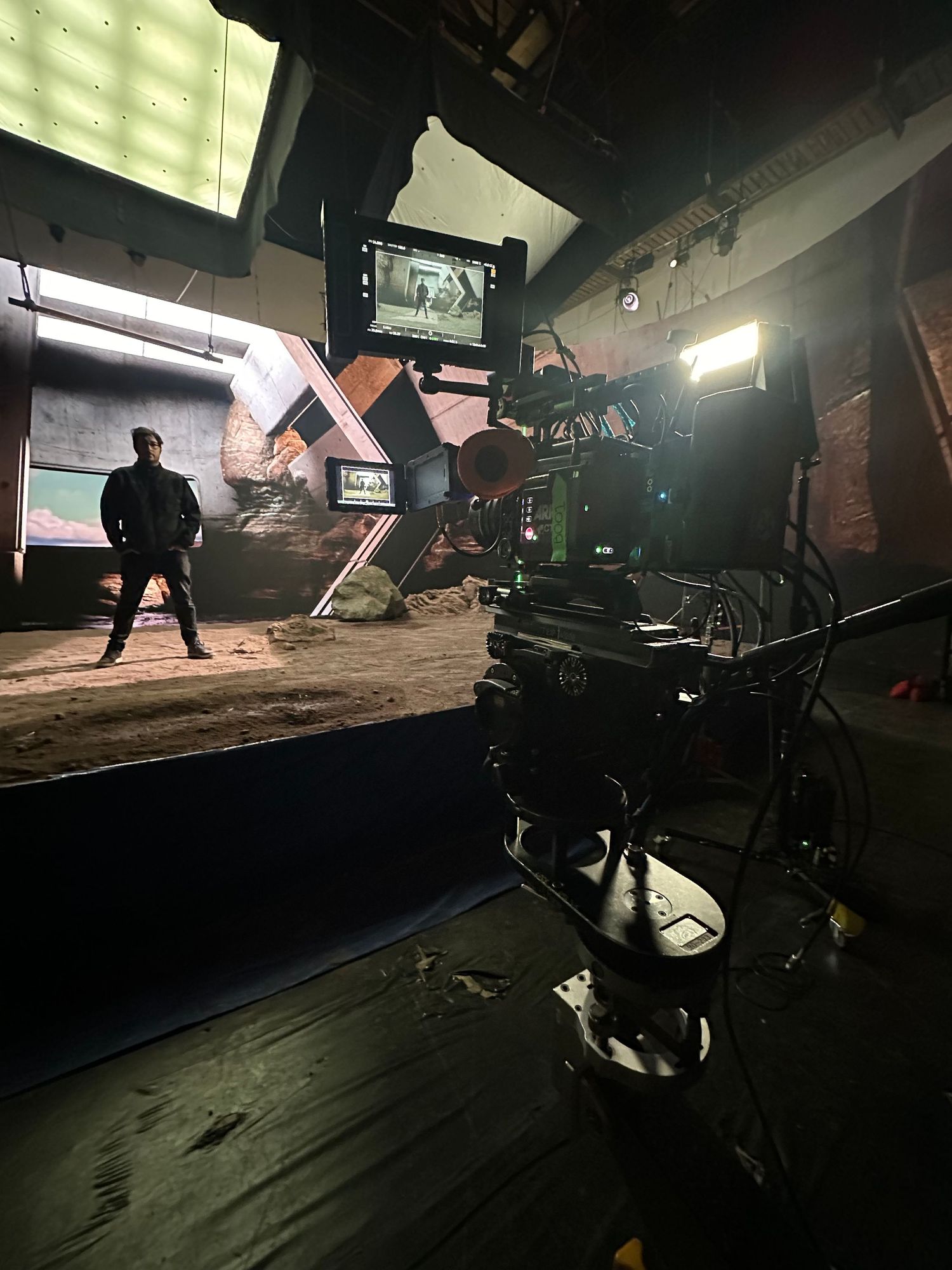 Professional cinema camera filming actor standing before dramatic LED virtual production set.