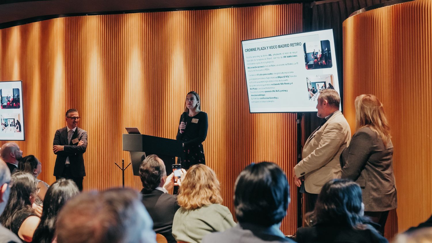 Speakers presenting on stage to an audience at a professional conference event.