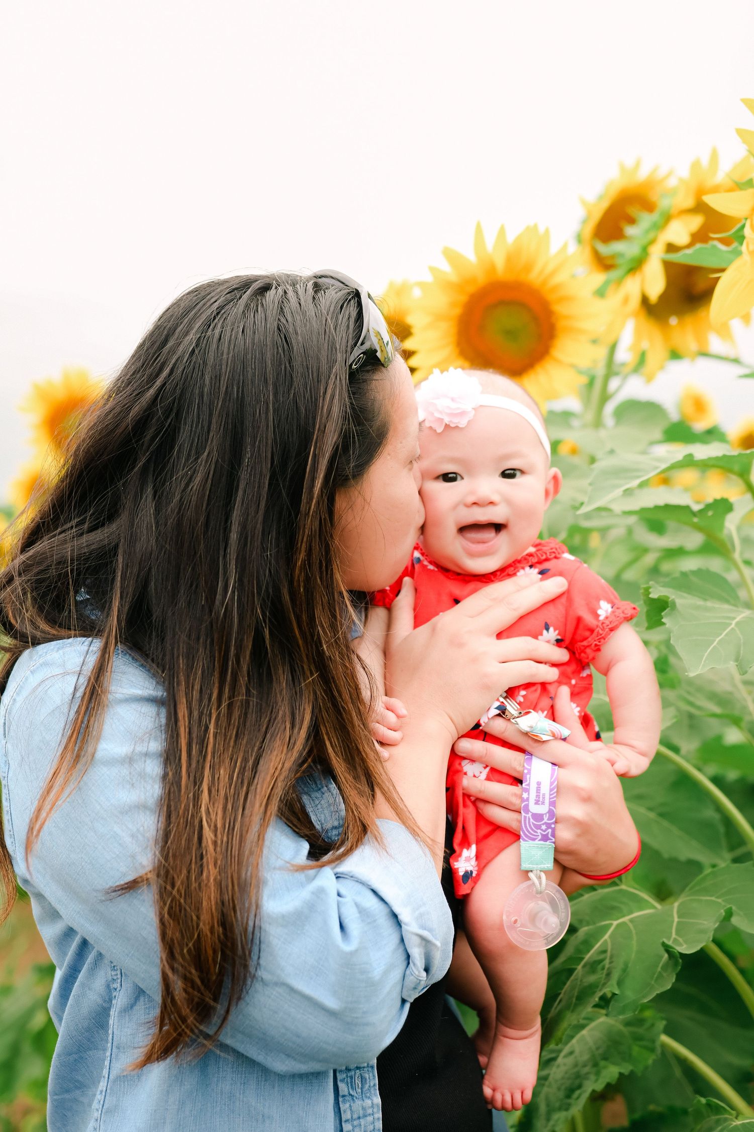 Mother and baby family photography session with a vibrant sunflower field in Minnesota.