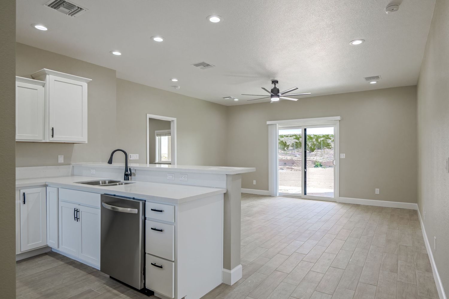 Open concept interior view of new home showing white kitchen cabinets and recessed lighting in neutral tones.