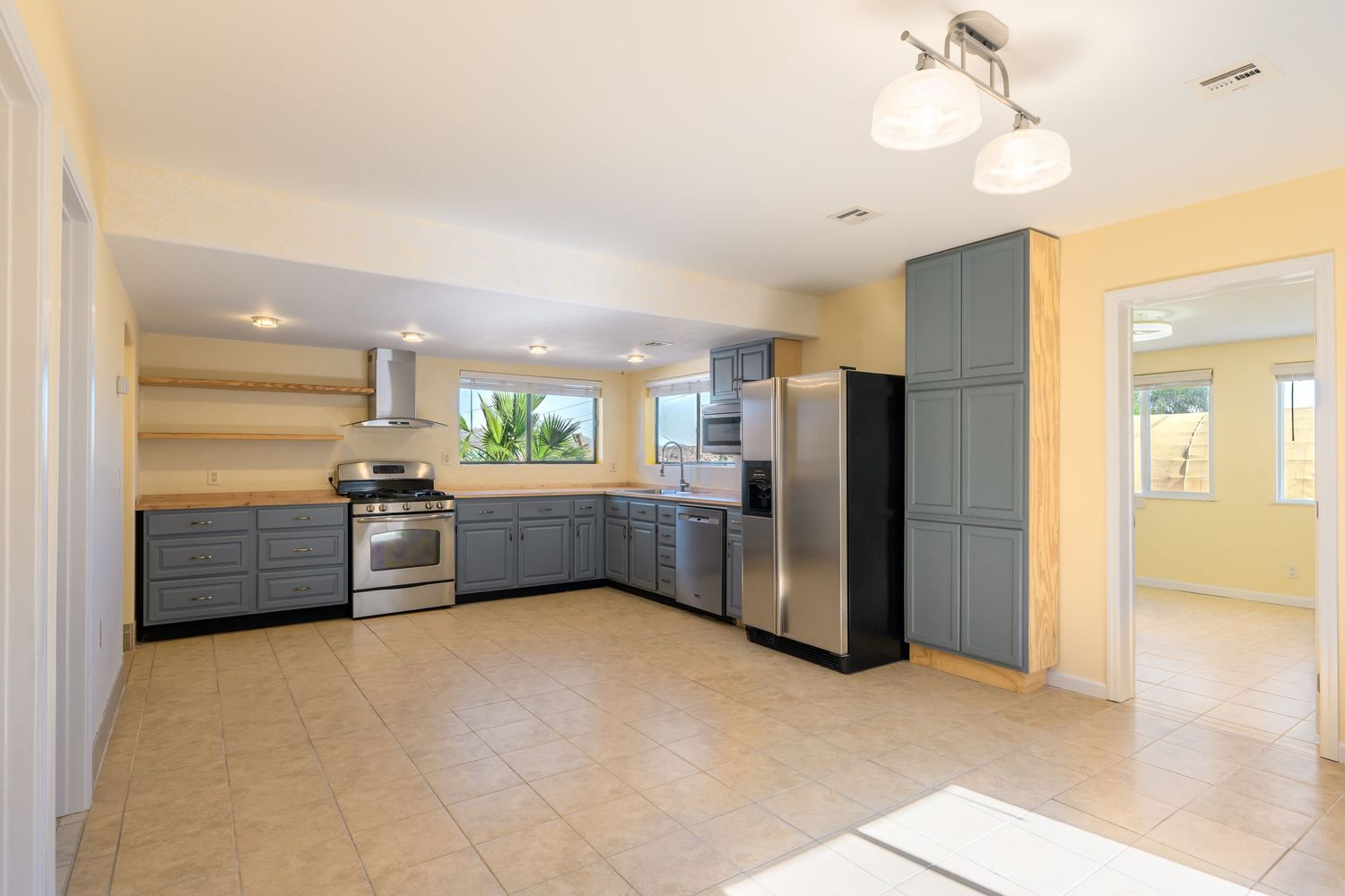 A modern interior panorama showing a spacious open floor plan with gray cabinets and beige walls.