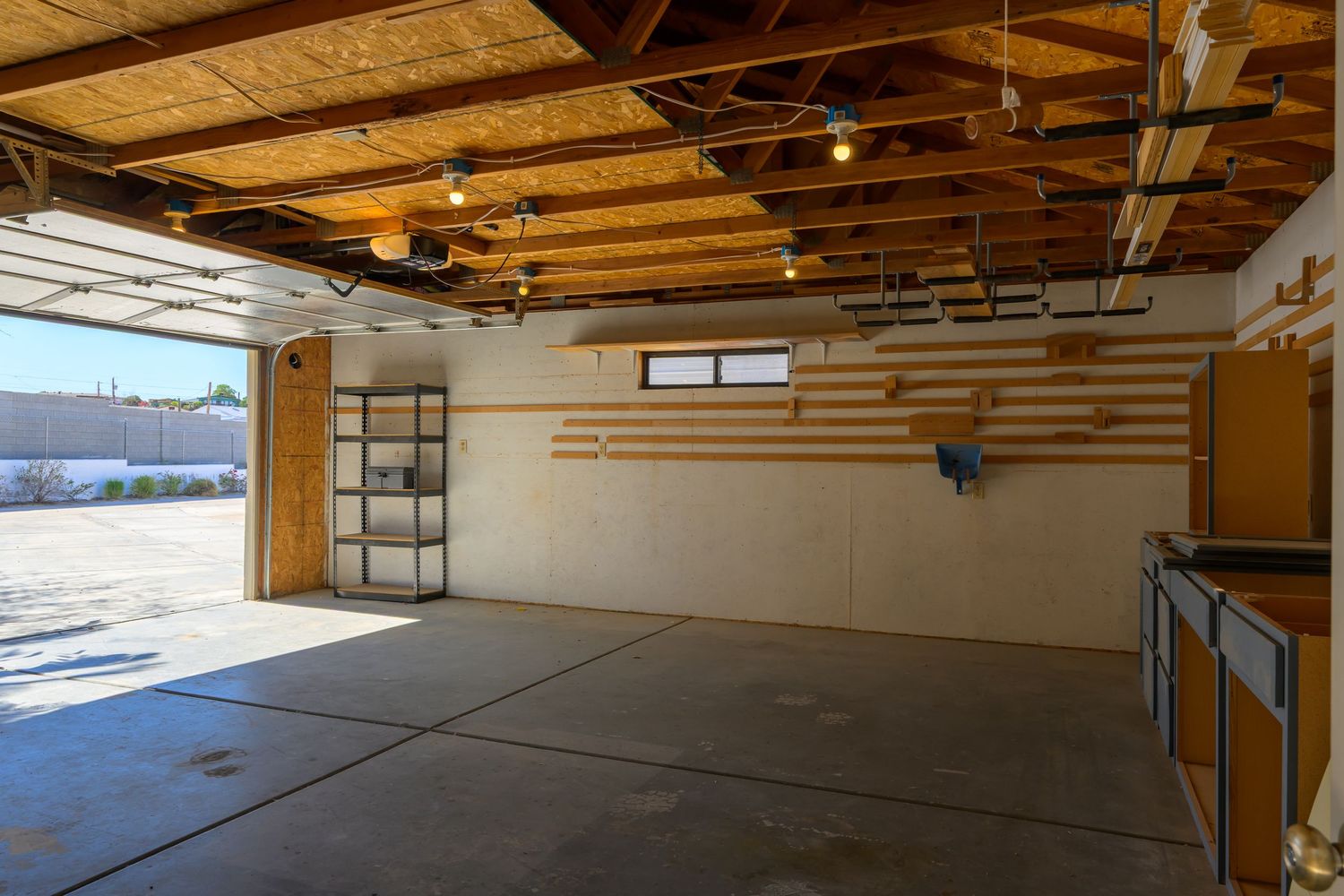 Large empty commercial garage interior with wooden beams and natural lighting from windows.