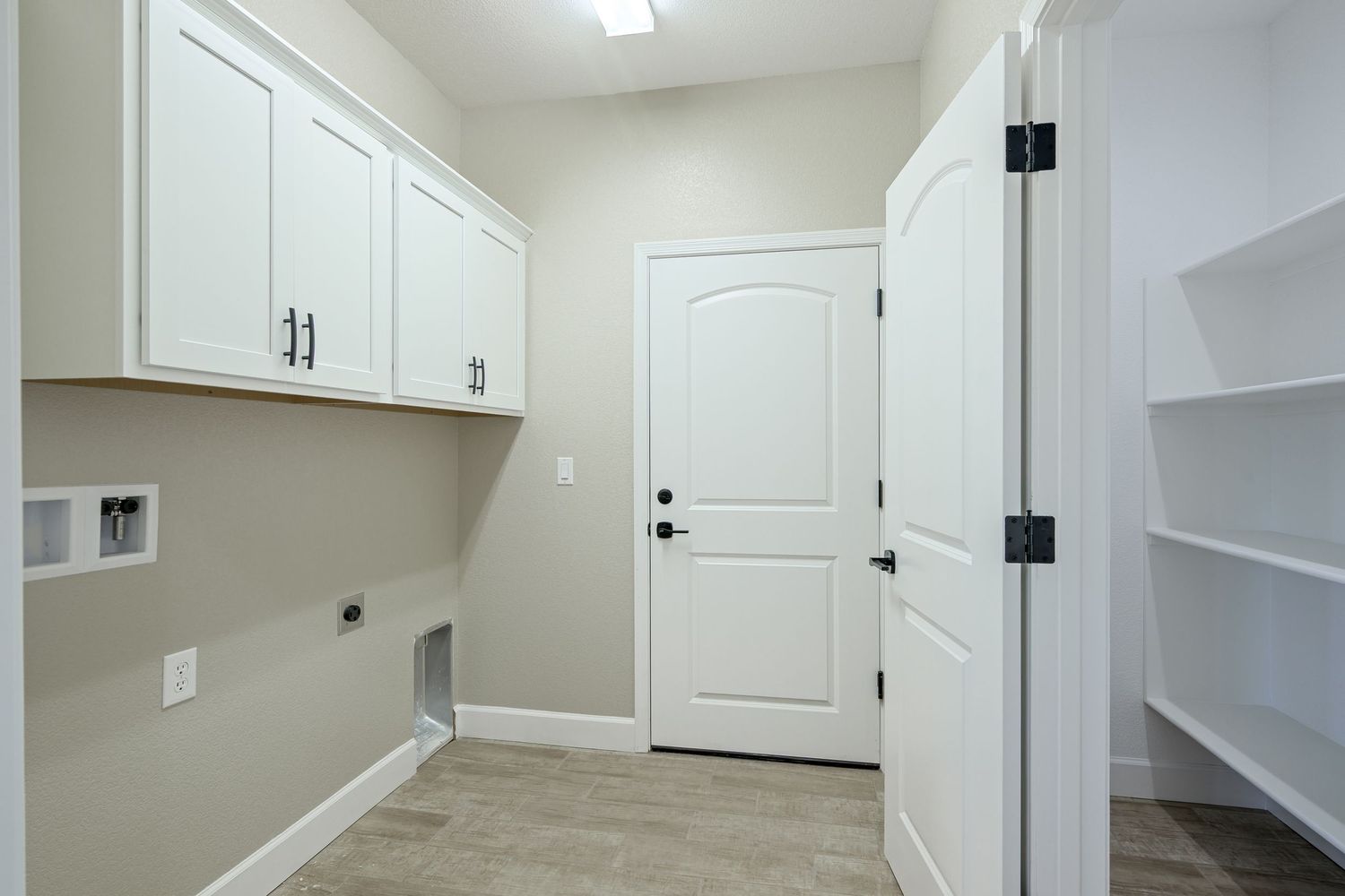 Long hallway in modern home with white walls, recessed lighting, and wood-look flooring extending into multiple rooms.